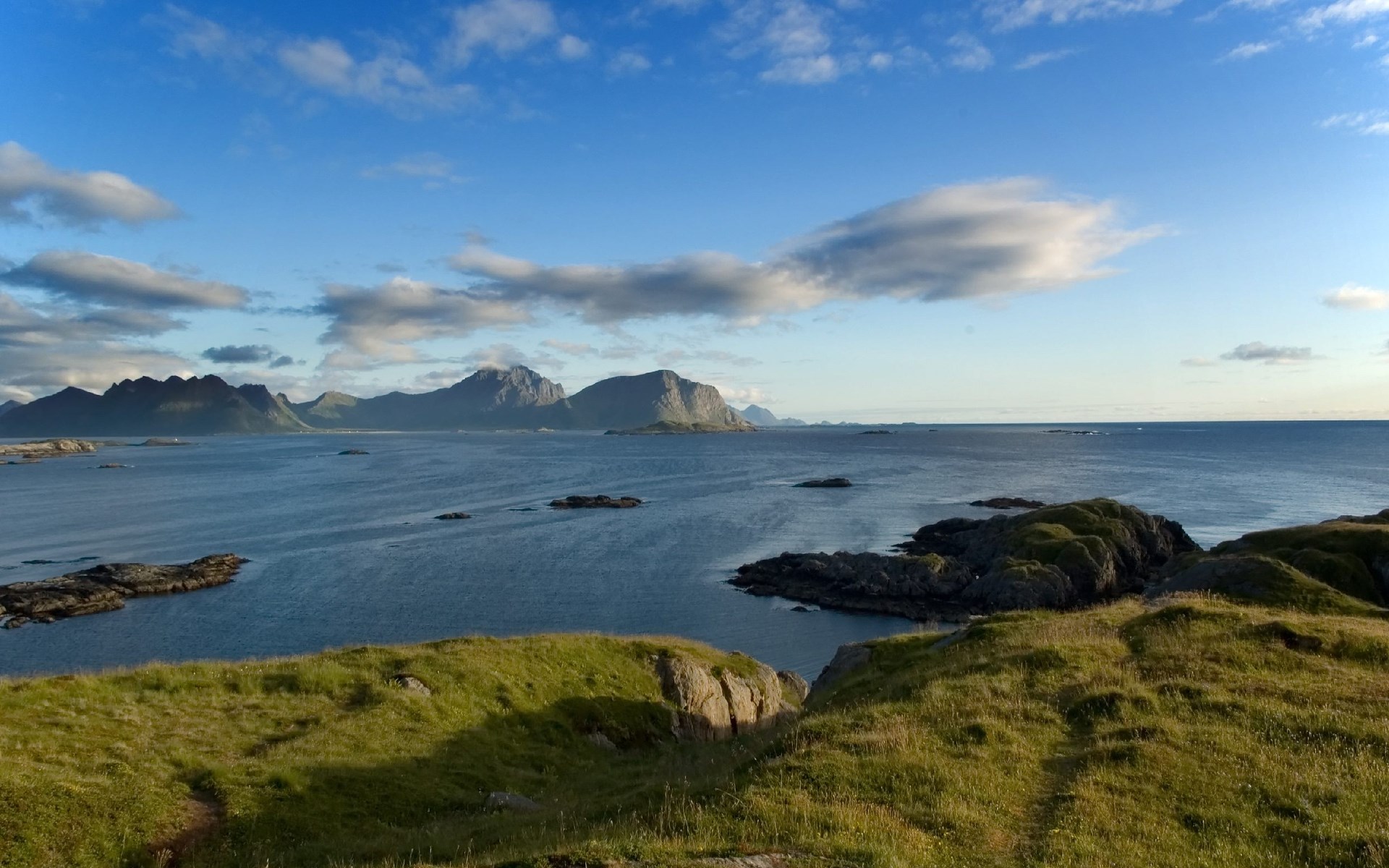 Rocky islands in the sea with mountains in the distance HD Wallpaper