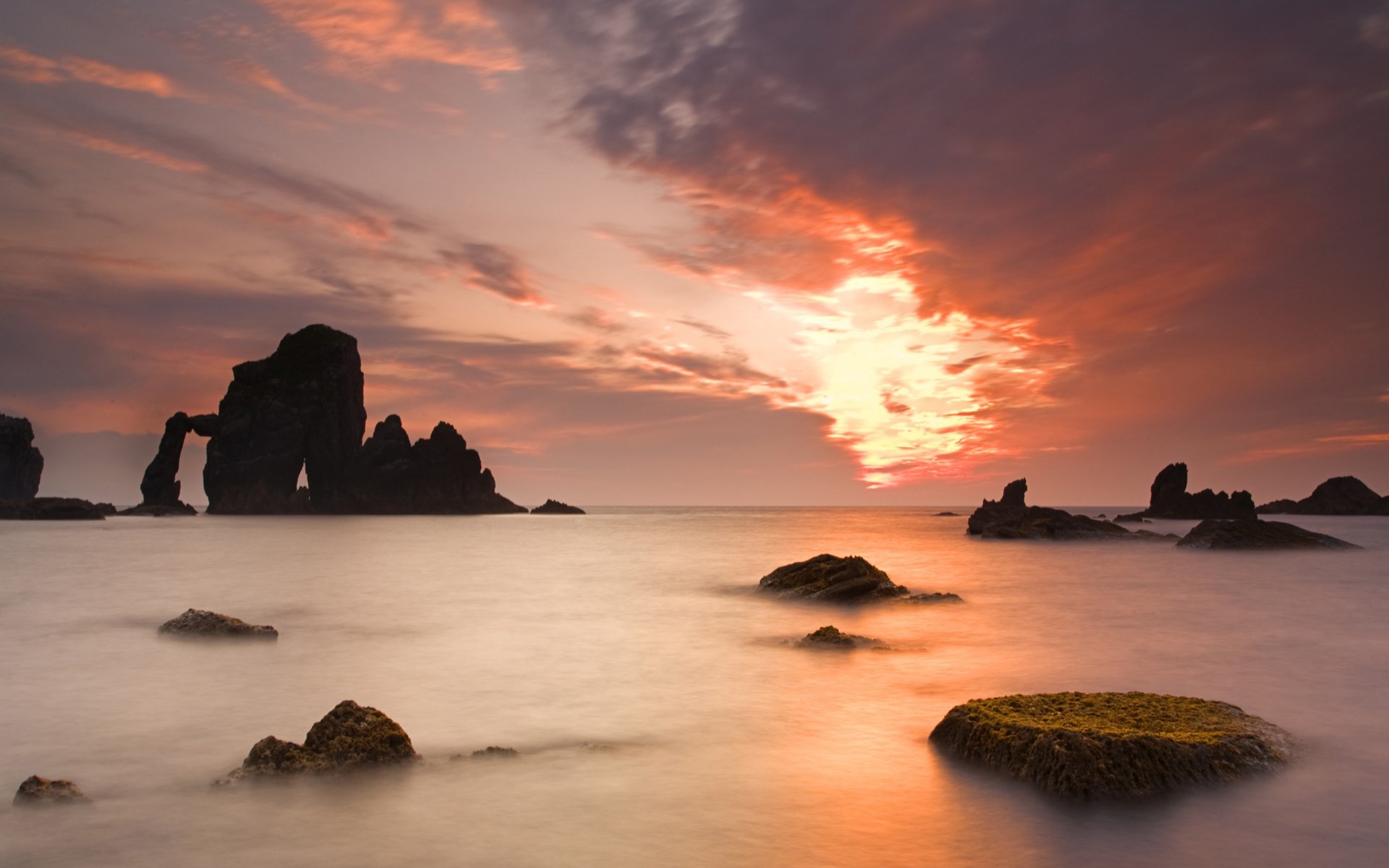 Rocky coastline at sunset with arch rock formation HD Wallpaper