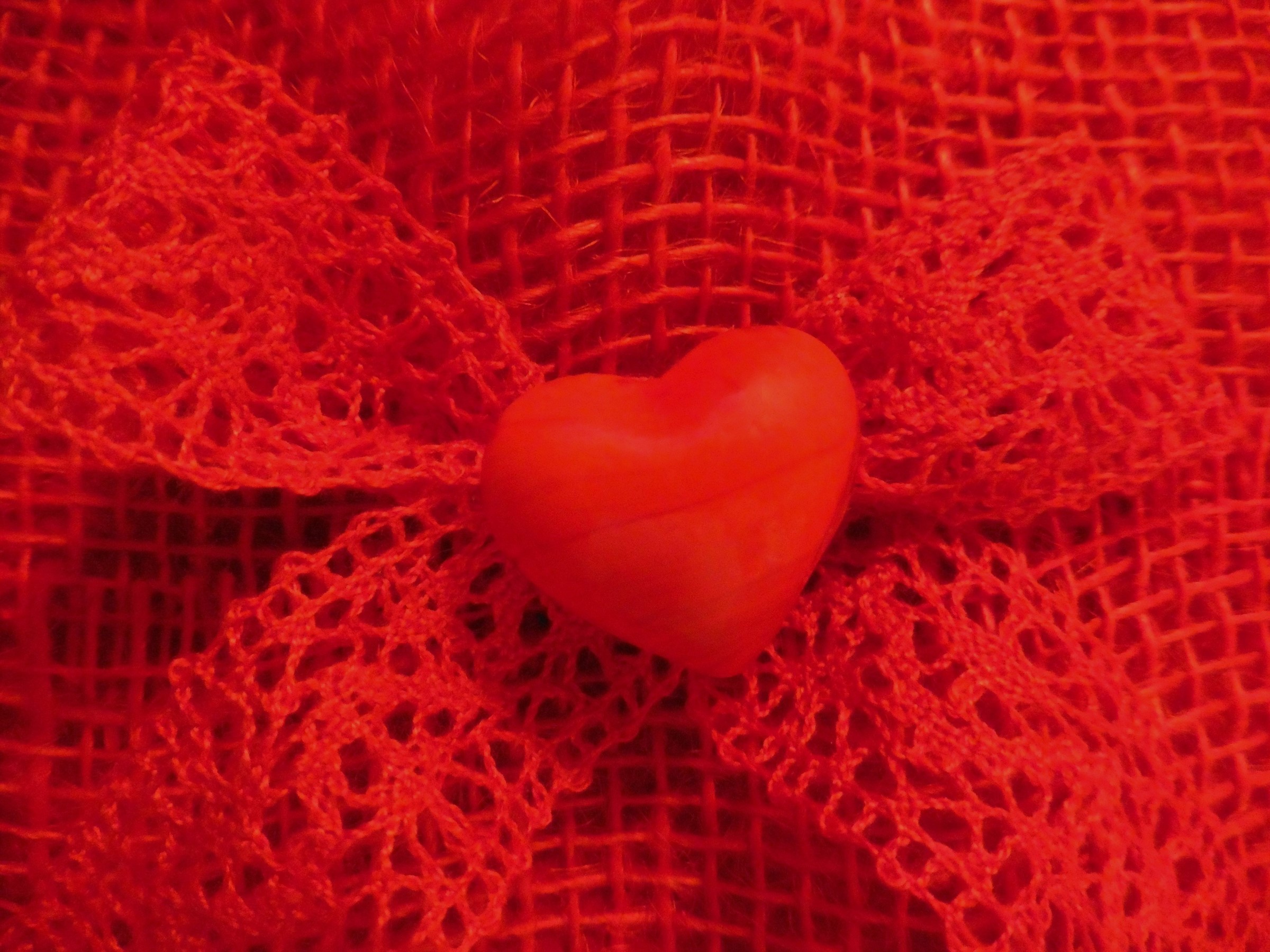 Red heart on red bowknot and fabric HD Wallpaper
