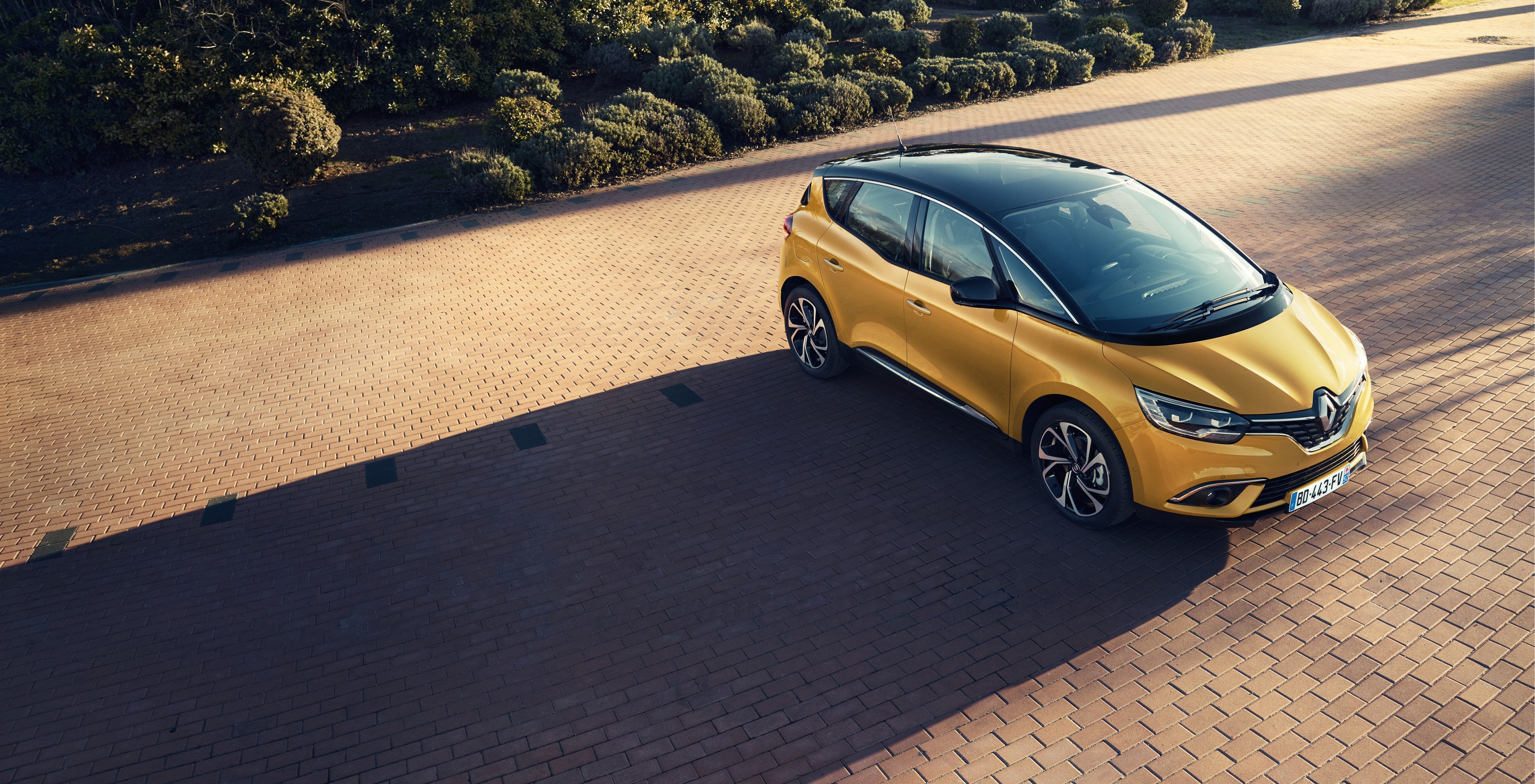 Yellow Renault Scenic parked on brick pavement HD Wallpaper