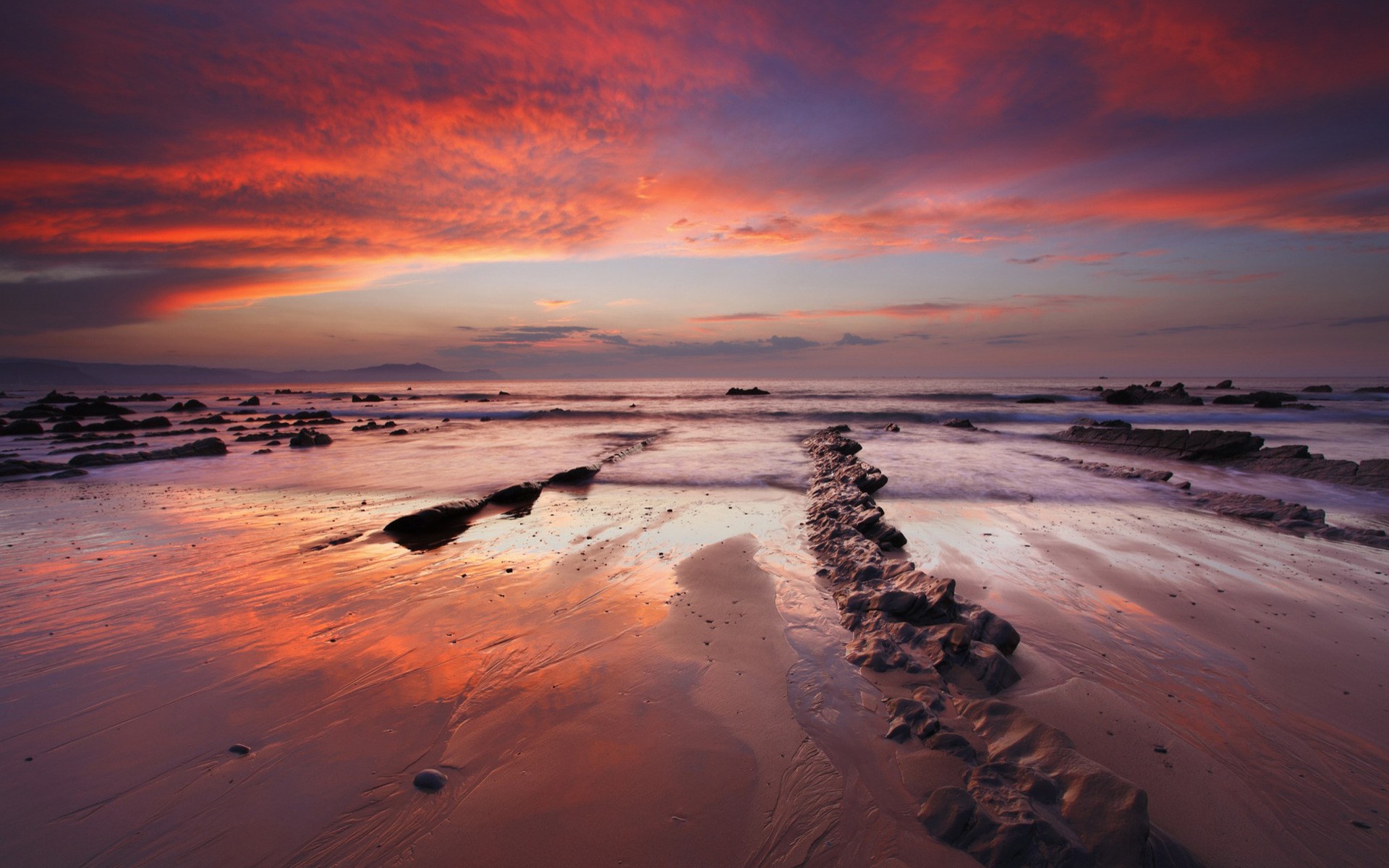 Sunset over a rocky beach with colorful clouds HD Wallpaper