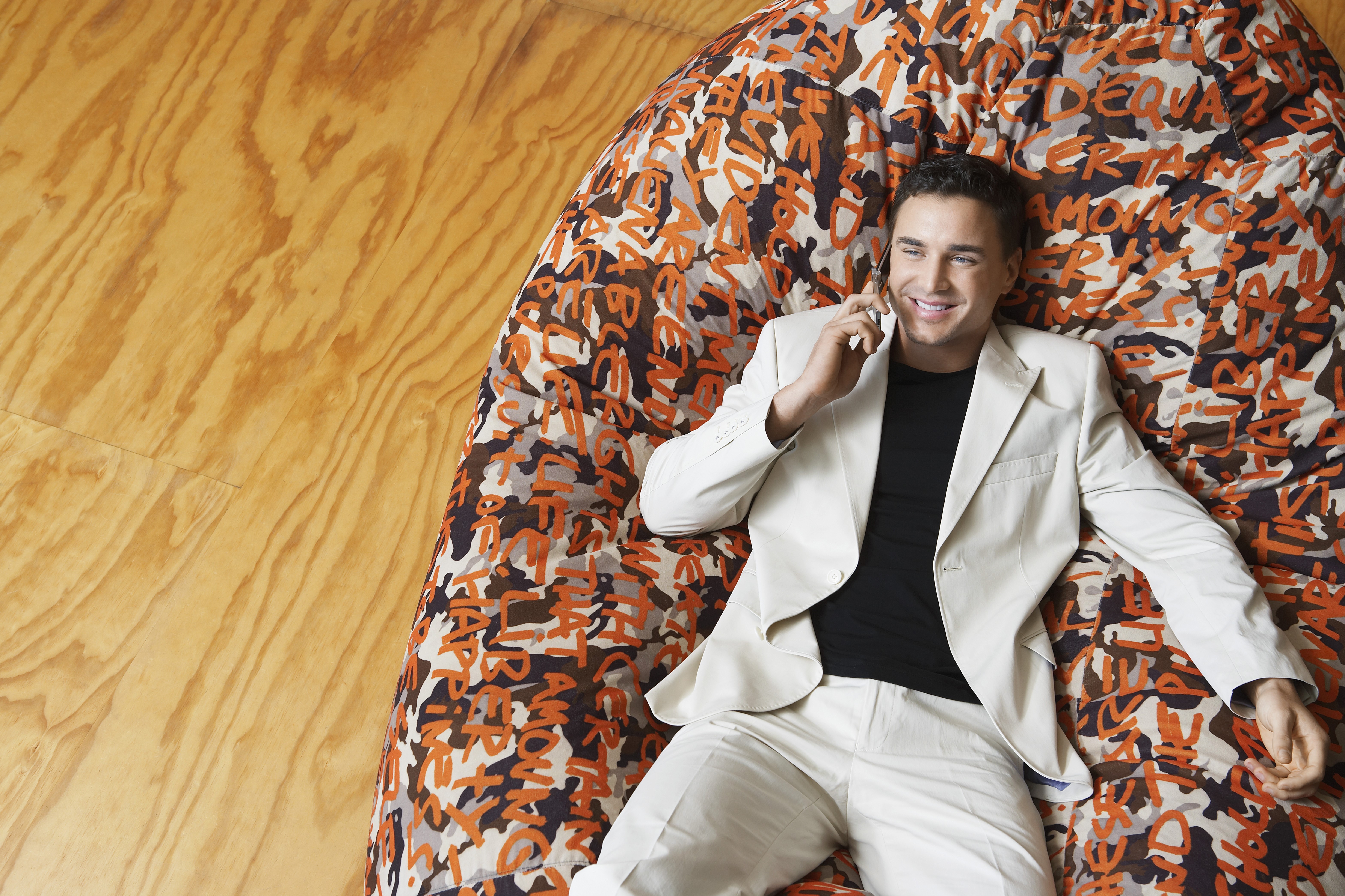 Man in suit talking on phone on patterned beanbag HD Wallpaper