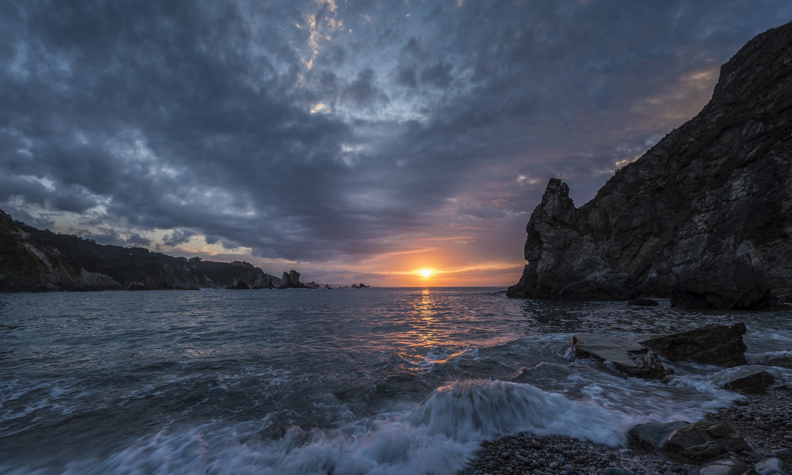 Sunset over a rocky bay with waves crashing on shore HD Wallpaper