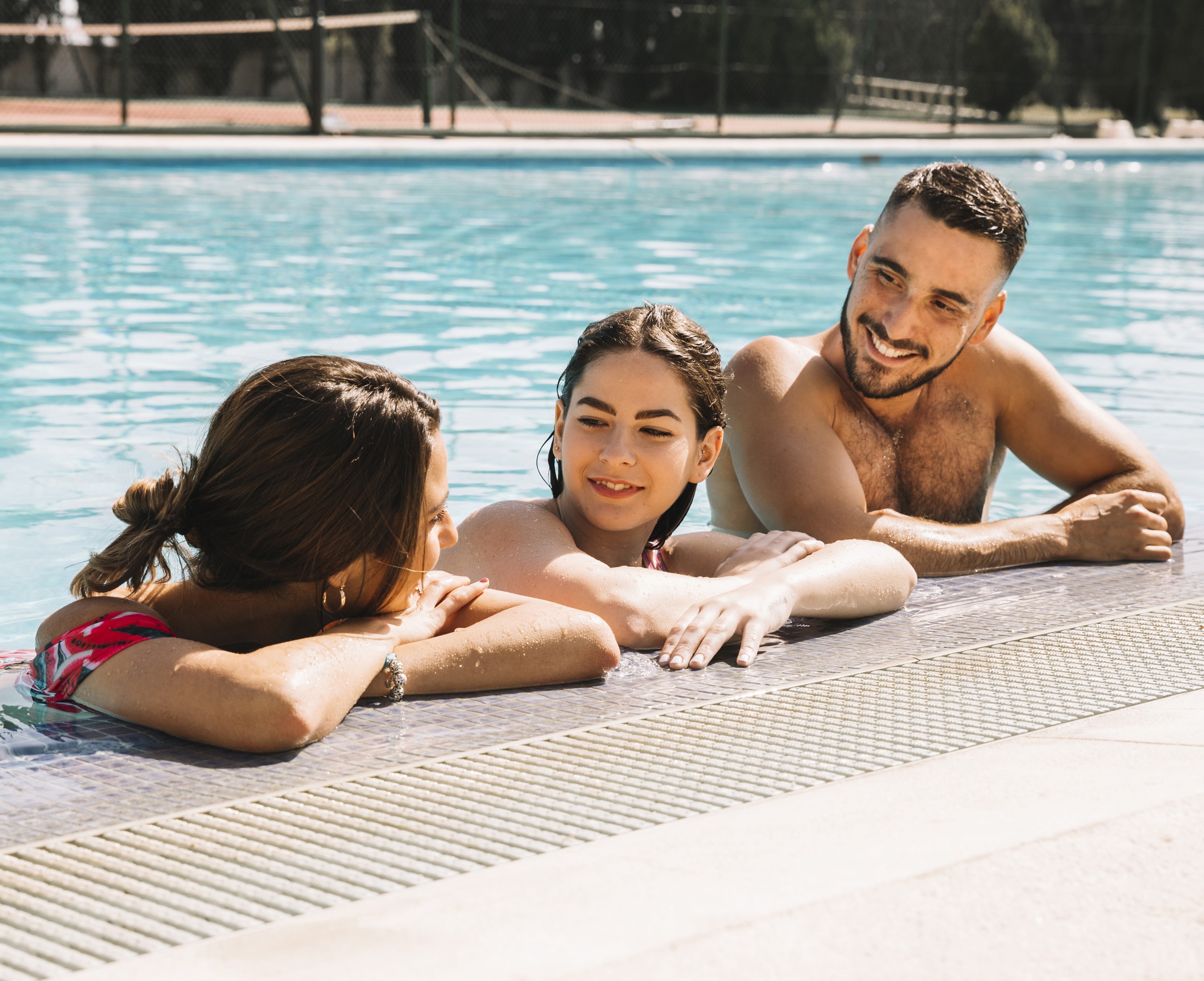 Three people smiling in a swimming pool HD Wallpaper