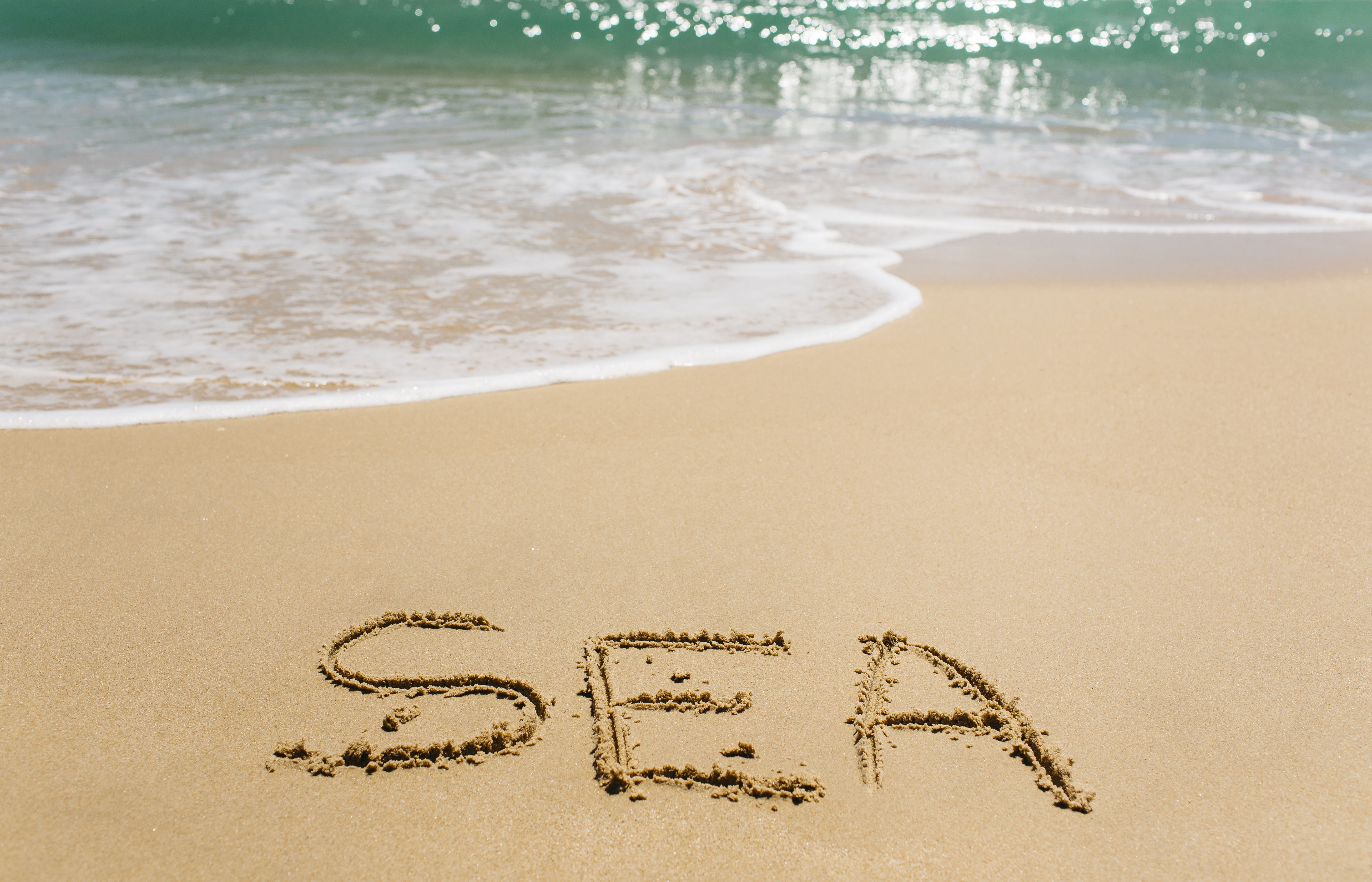 Sea written in sand with ocean waves HD Wallpaper
