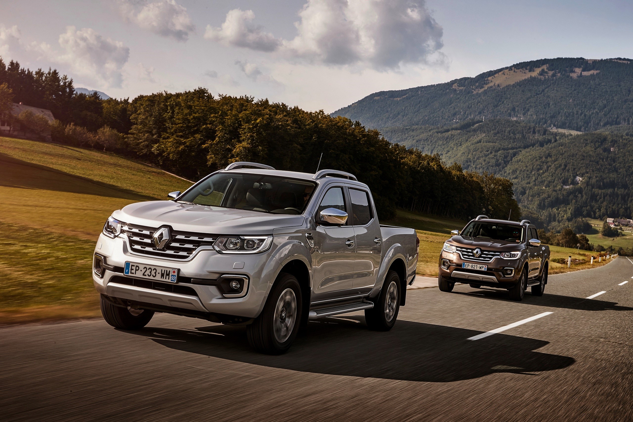 Two Renault Alaskan pickup trucks on a road HD Wallpaper