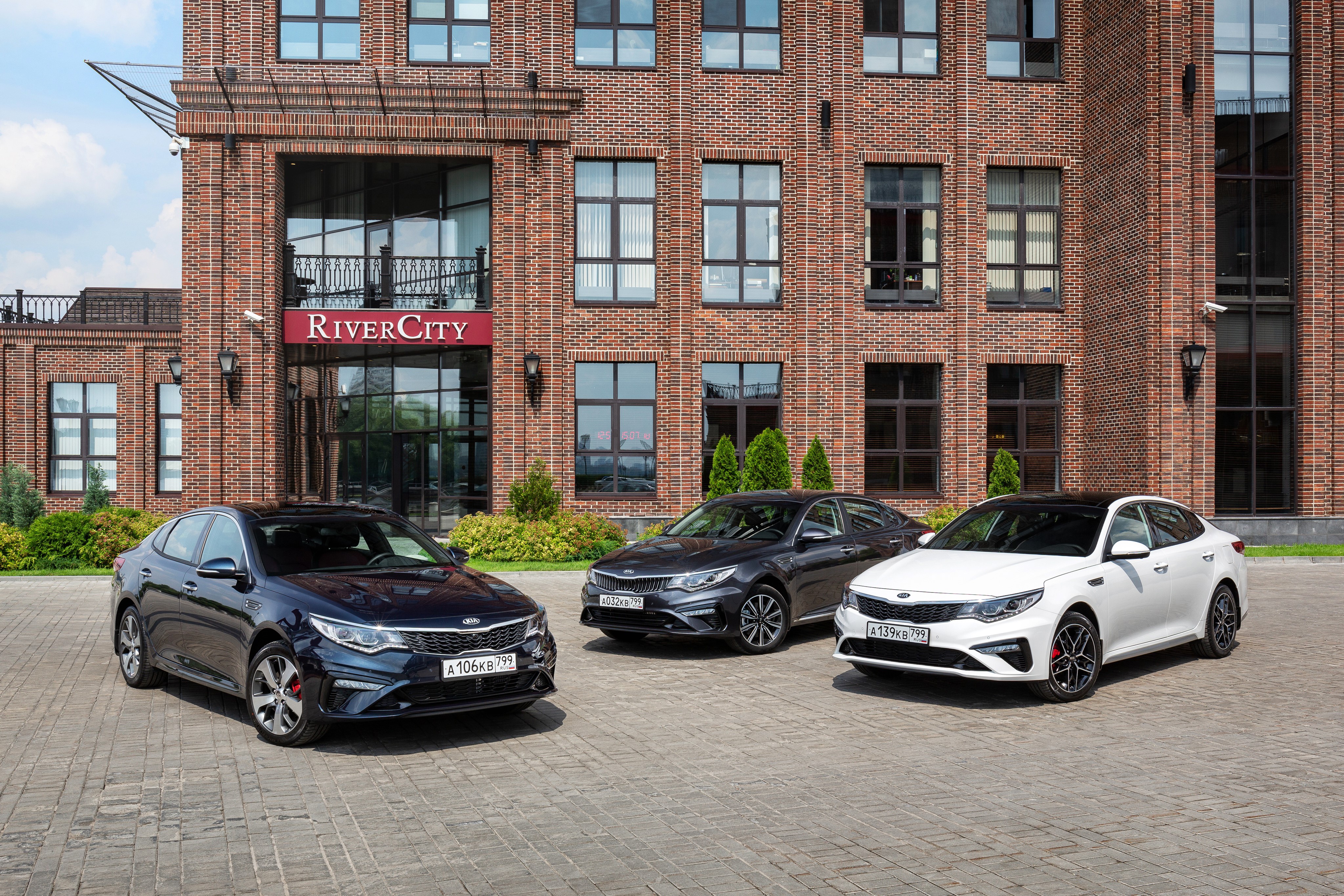 Three Kia Optima Sedans in front of River City building HD Wallpaper