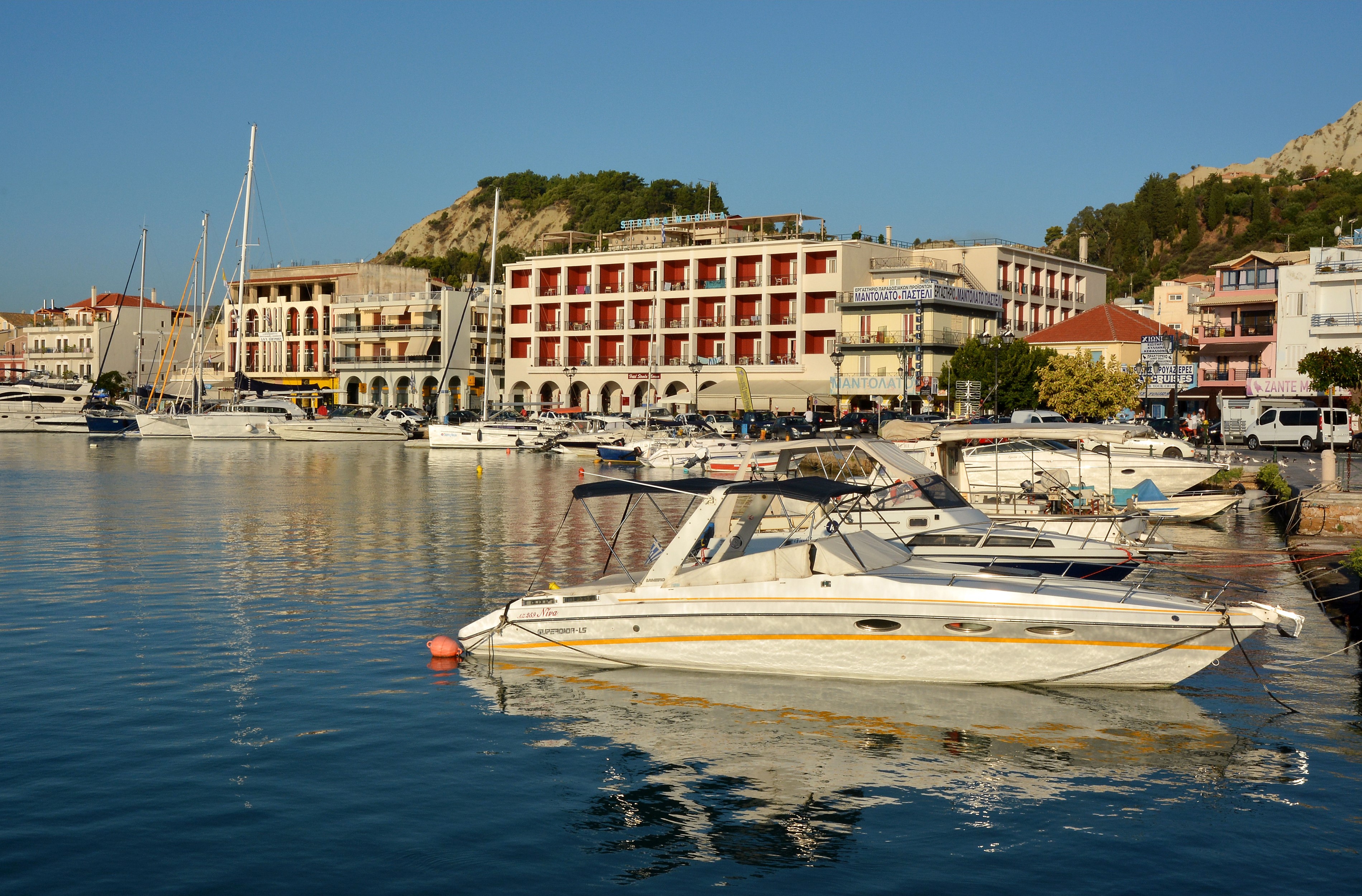 Boats docked in a harbor with buildings and a hill in Zakynthos, Greece HD Wallpaper
