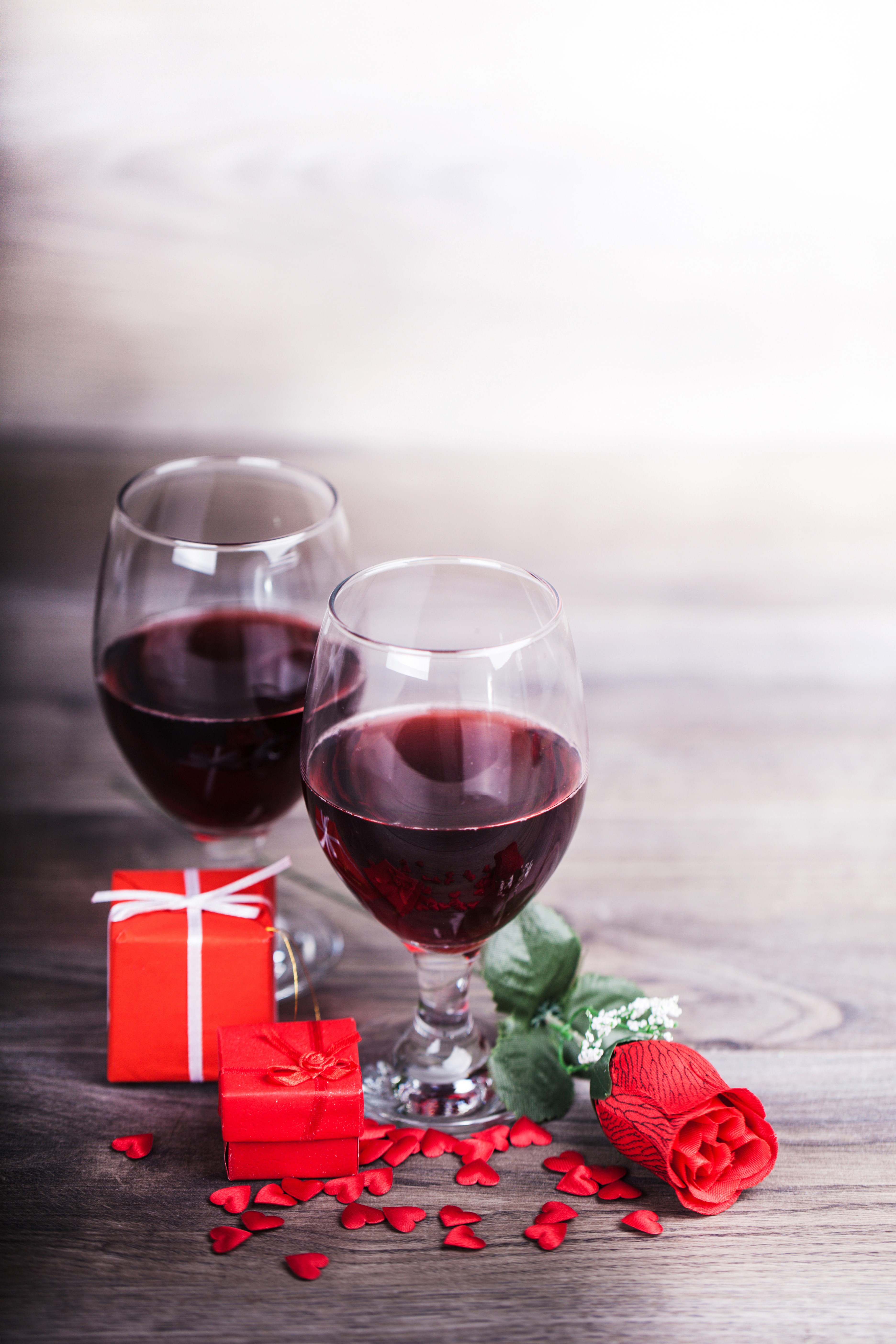 Two glasses of red wine with gifts and a rose HD Phone Wallpaper