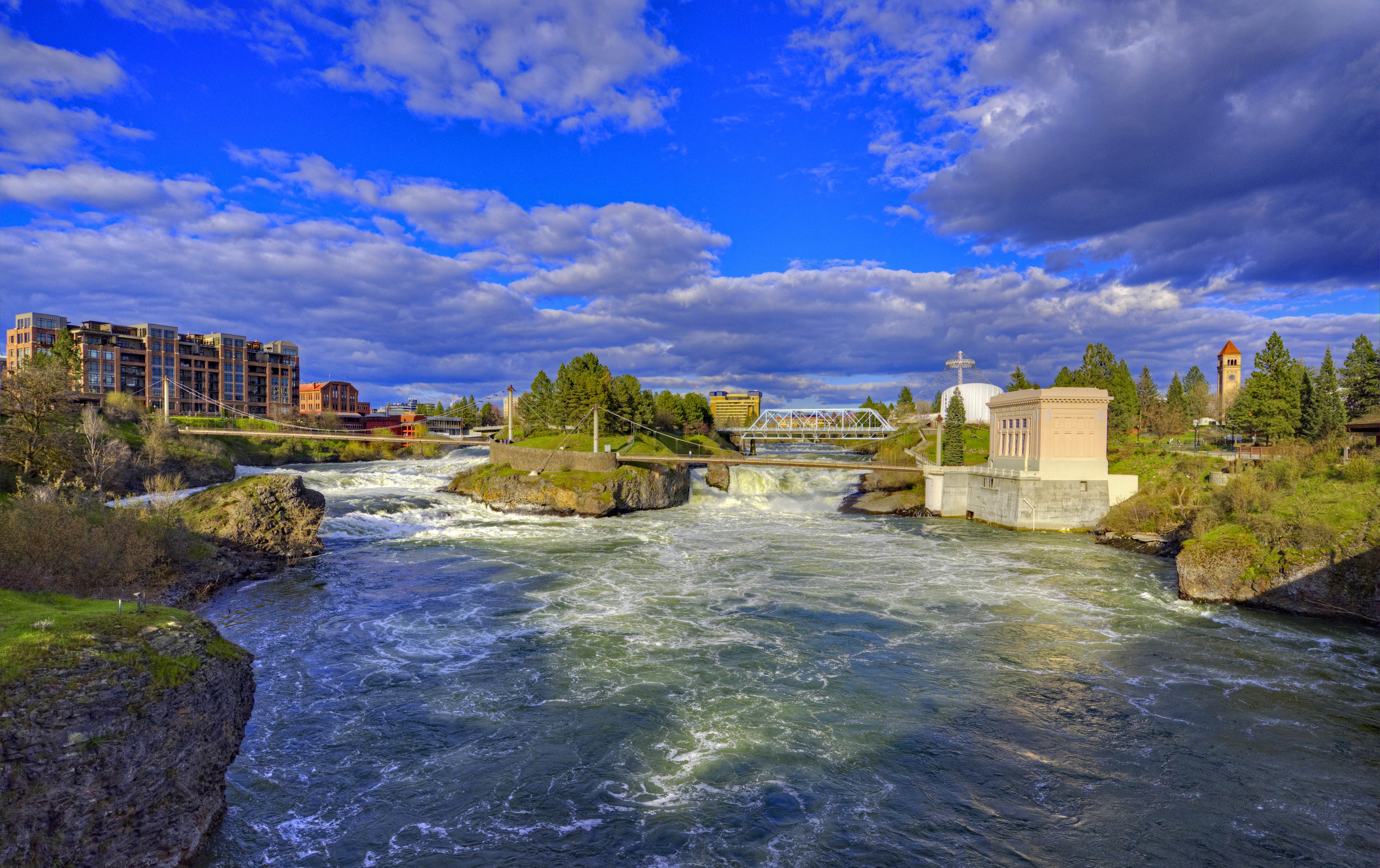 Spokane River with bridges and buildings under a cloudy sky HD Wallpaper