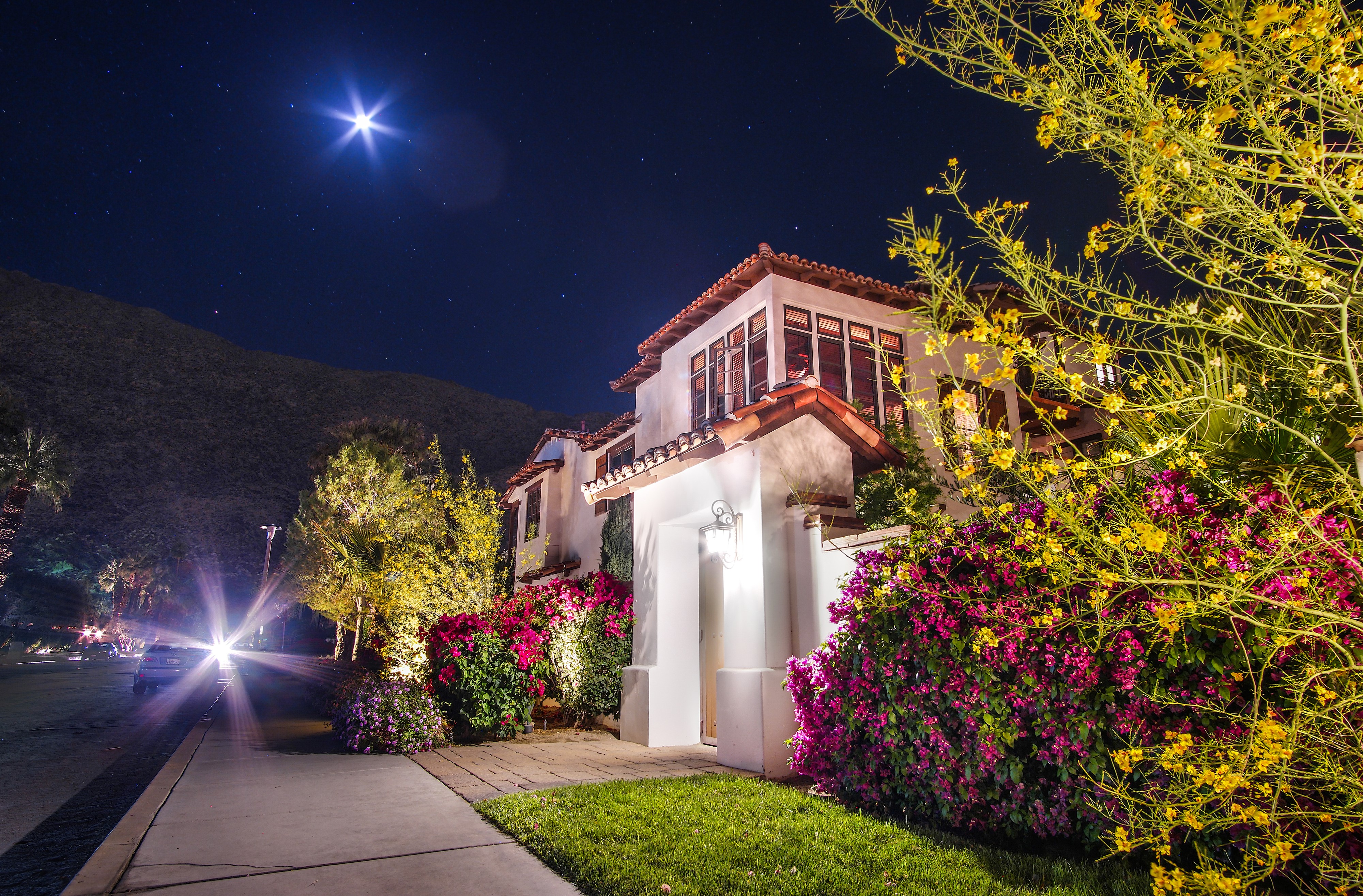 House at night with moon and car lights in California HD Wallpaper