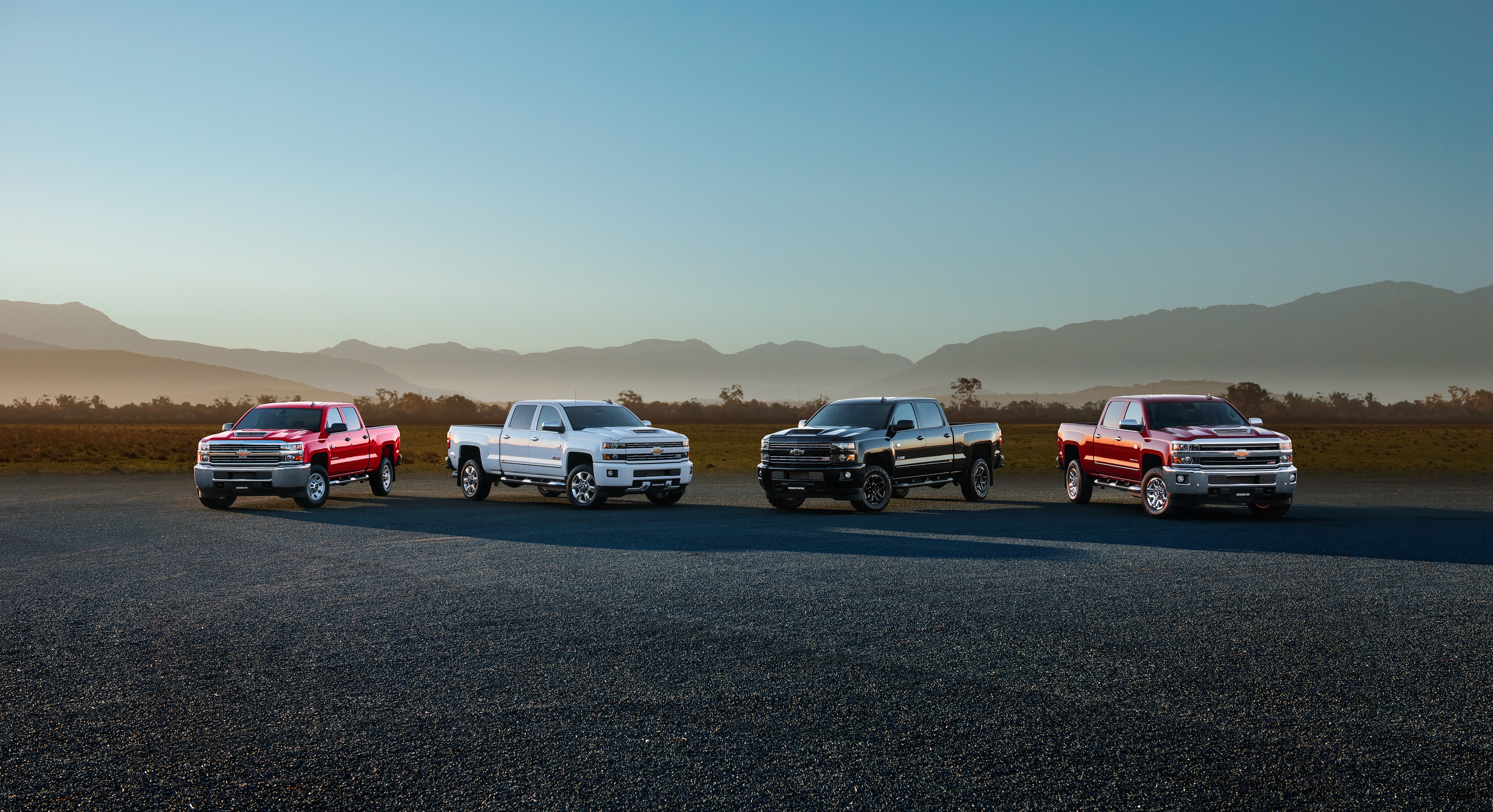 Four Chevrolet Pickup Trucks in a Landscape HD Wallpaper