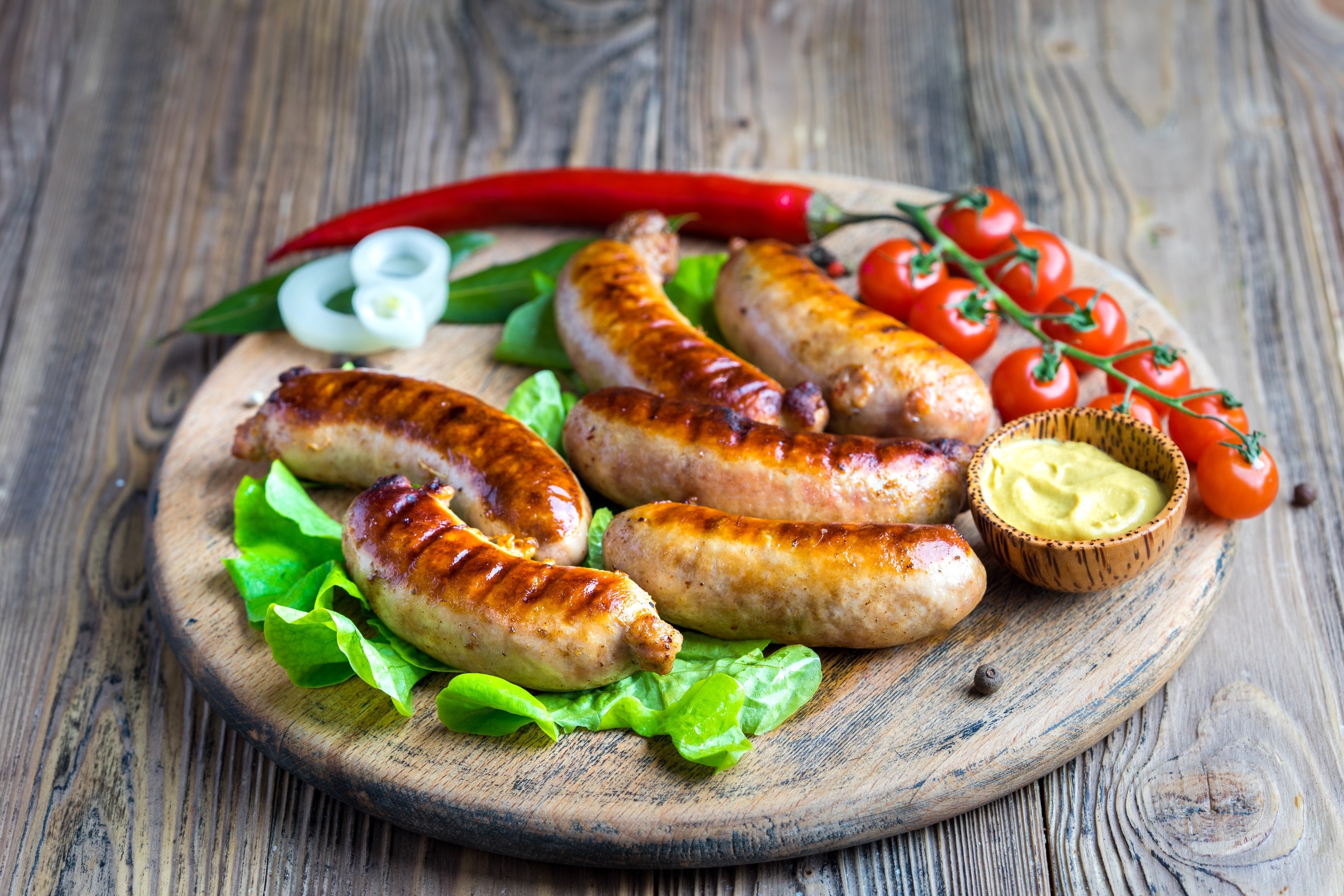 Grilled sausages with tomatoes and mustard on a wooden board HD Wallpaper