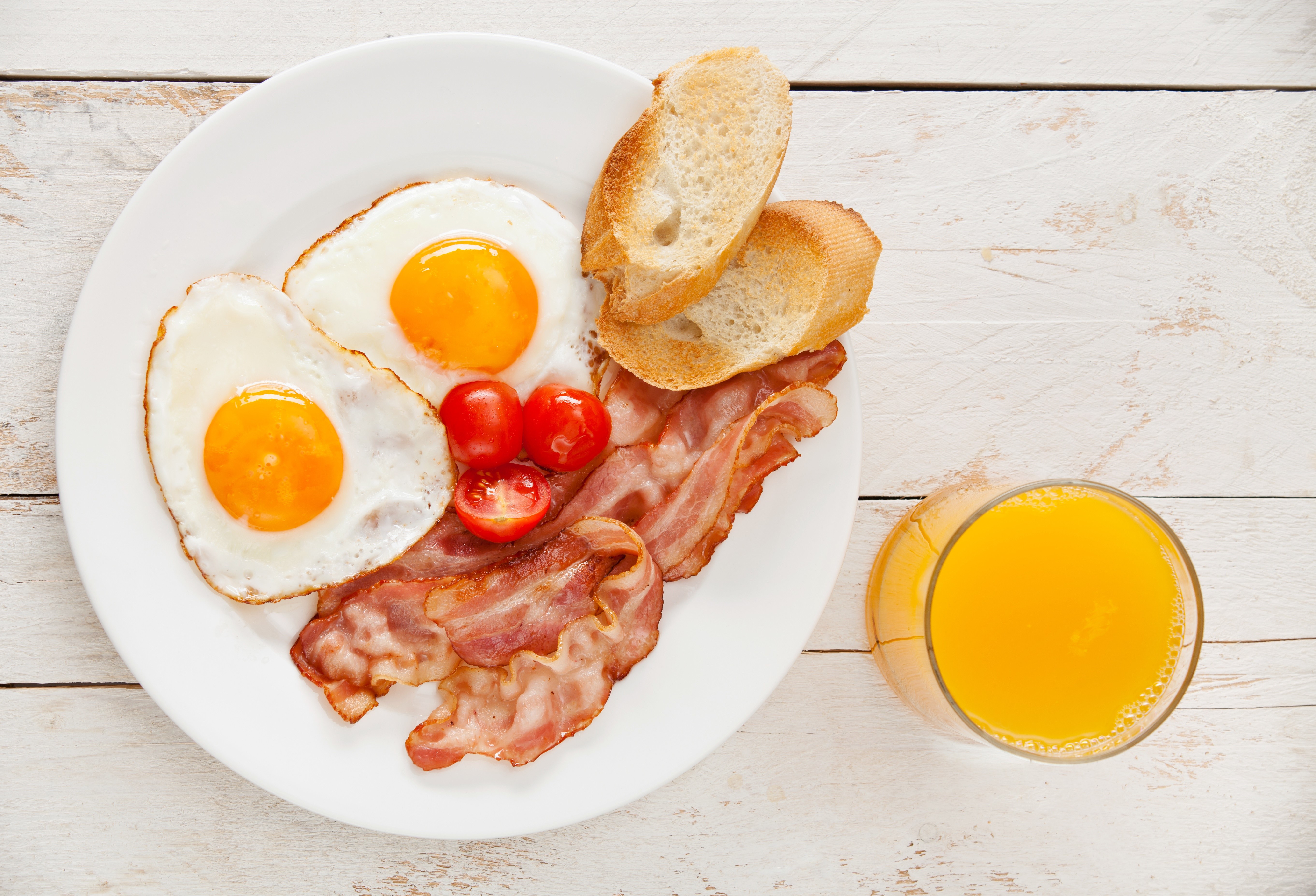 Fried eggs, bacon, tomatoes, bread, and orange juice on a plate HD Wallpaper