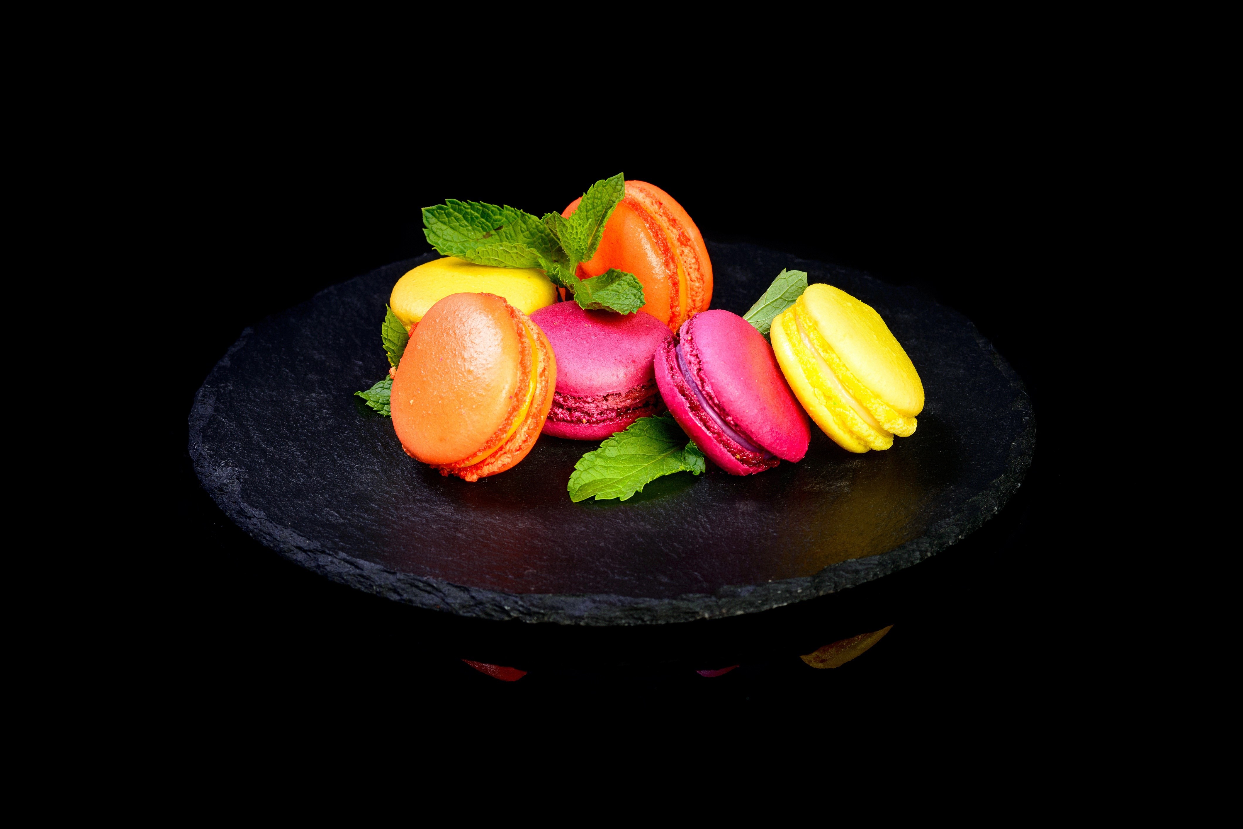 Colorful macarons with mint leaves on black slate HD Wallpaper