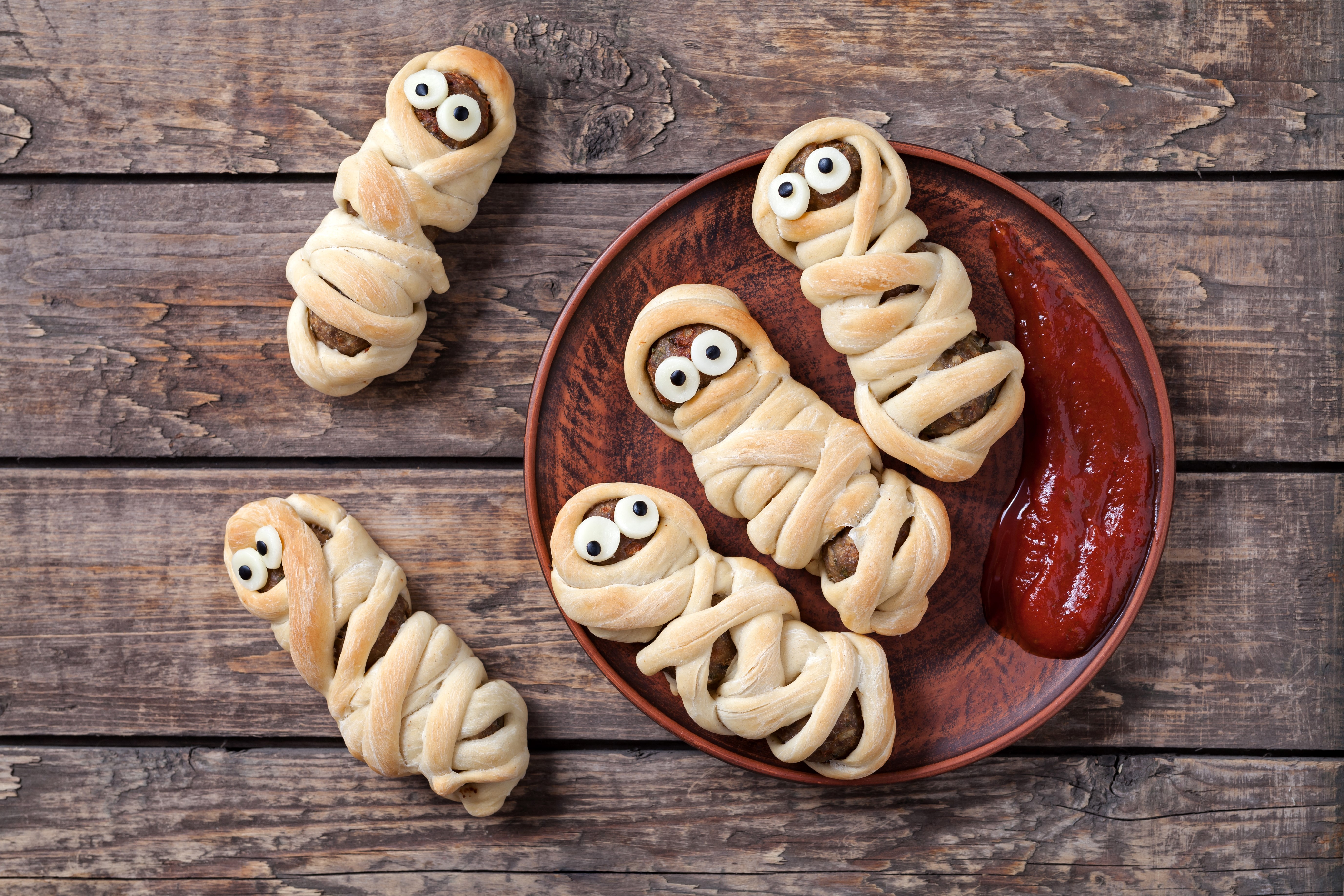 Halloween mummy meat pies with ketchup on a wooden table HD Wallpaper