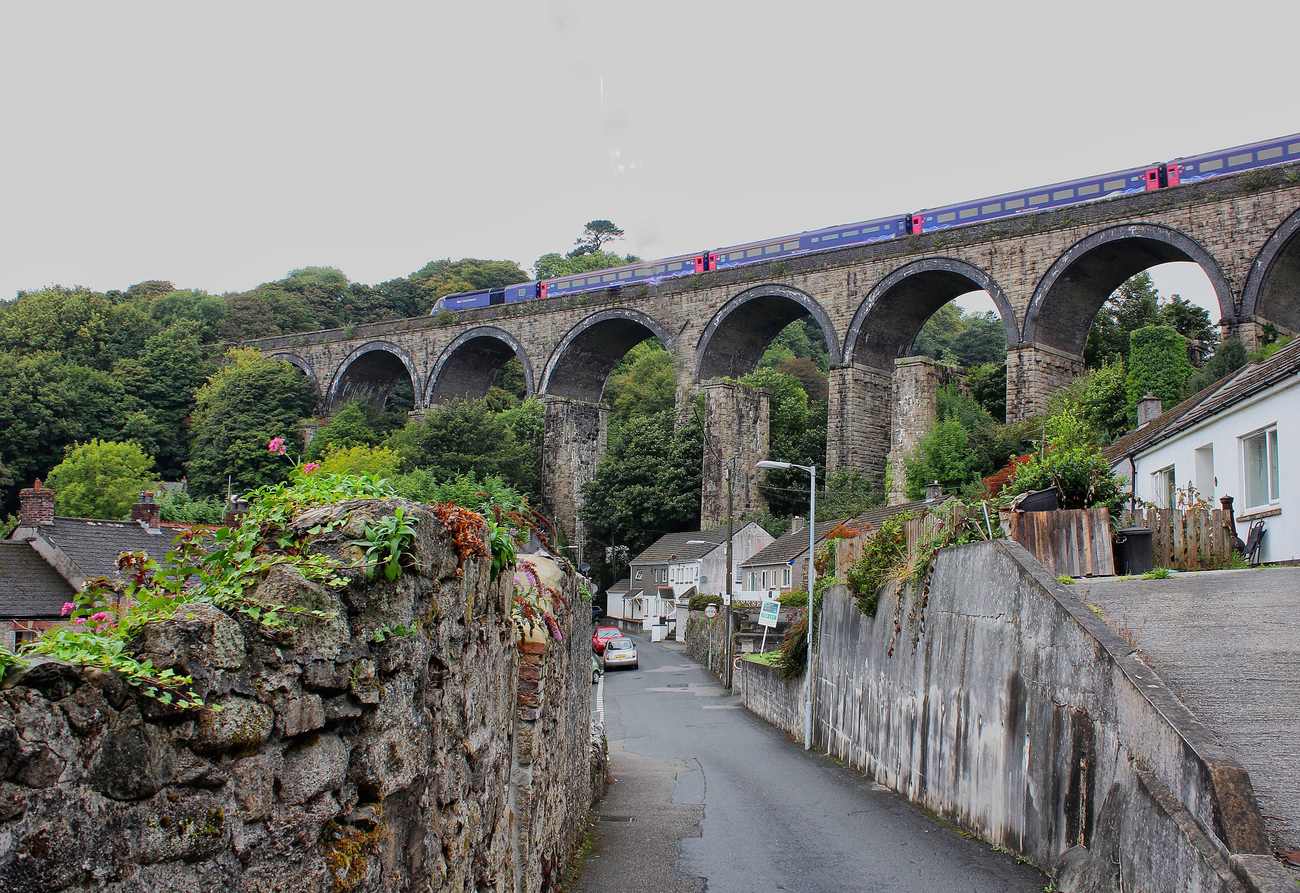 Train crossing a stone viaduct over a village in Saint Austell, United Kingdom HD Wallpaper