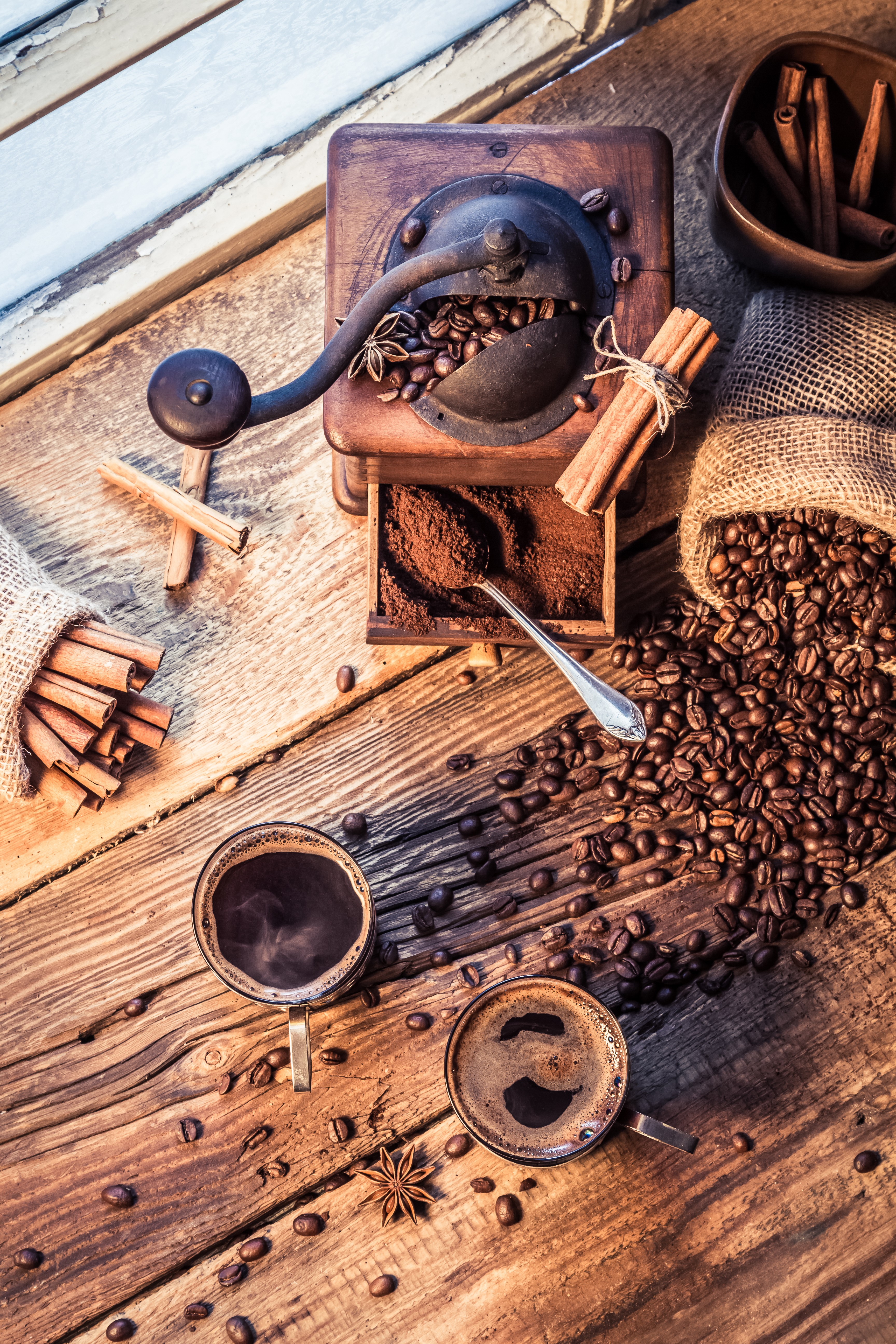 Coffee grinder with beans, cinnamon, and cups of coffee HD Phone Wallpaper