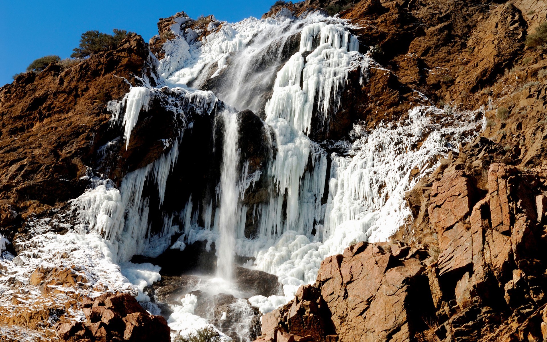 Frozen waterfall cascading down a rocky mountainside HD Wallpaper