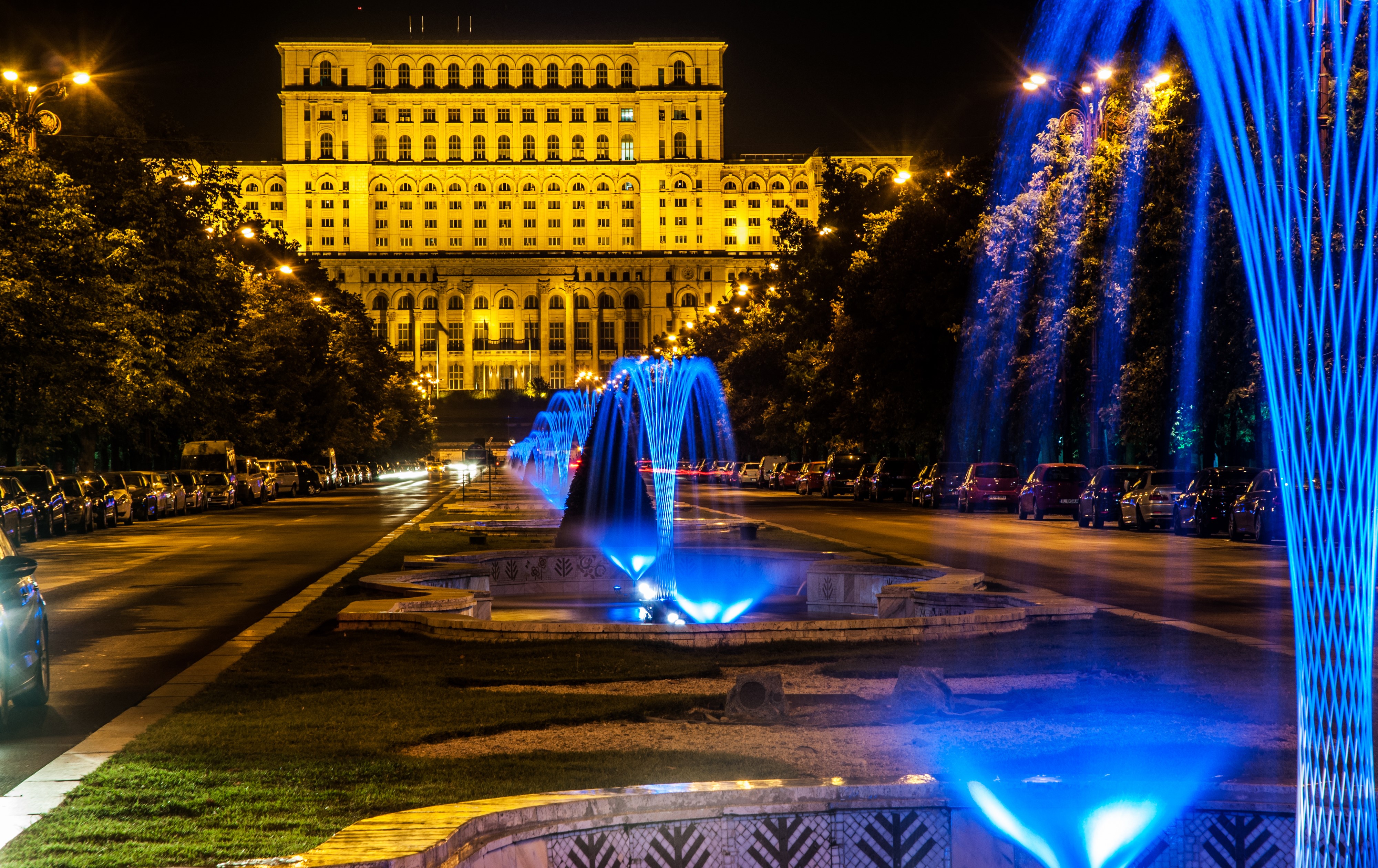 Palace of the Parliament and illuminated fountains in Bucharest, Romania at night HD Wallpaper