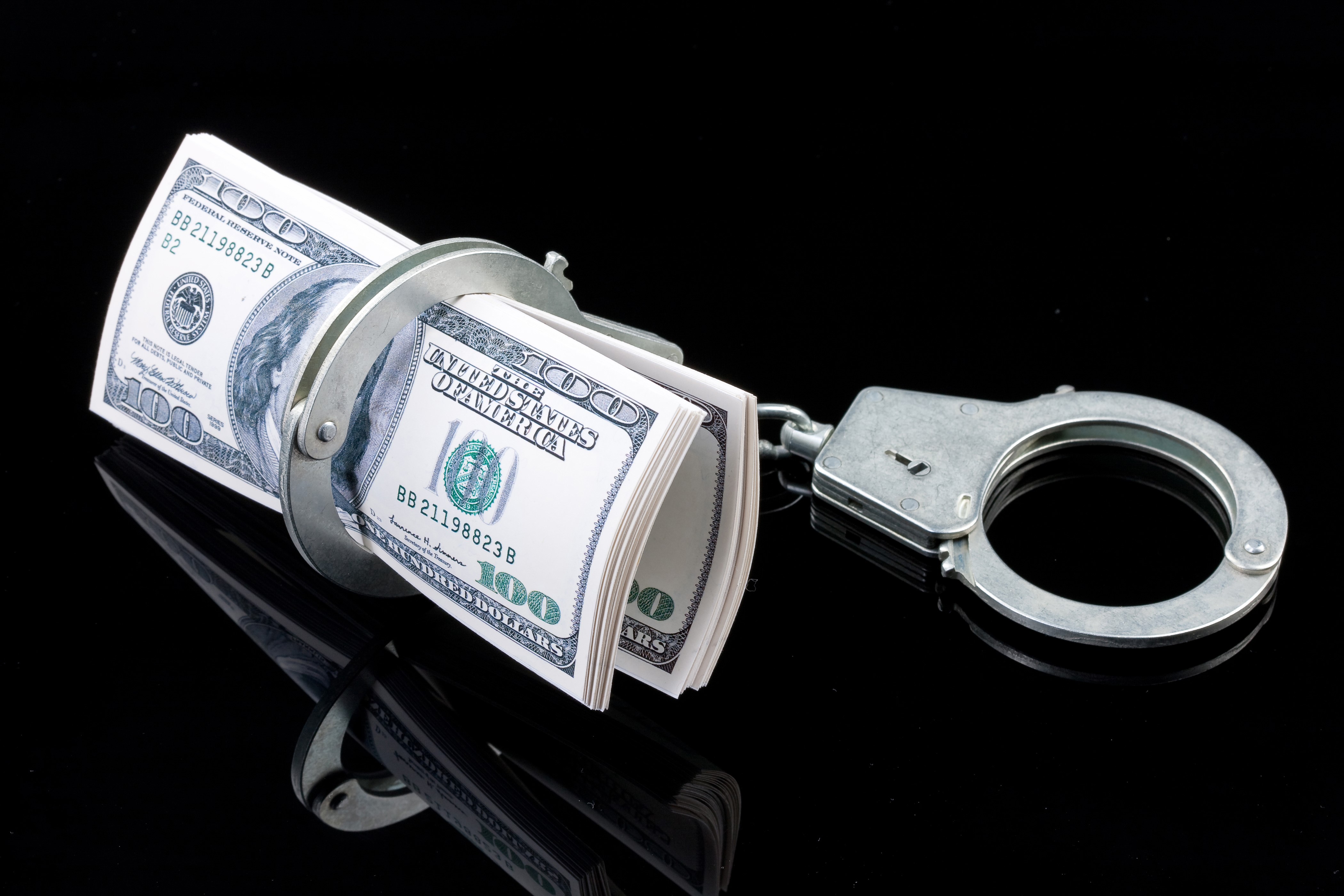 Handcuffs on a roll of US Dollar banknotes HD Wallpaper