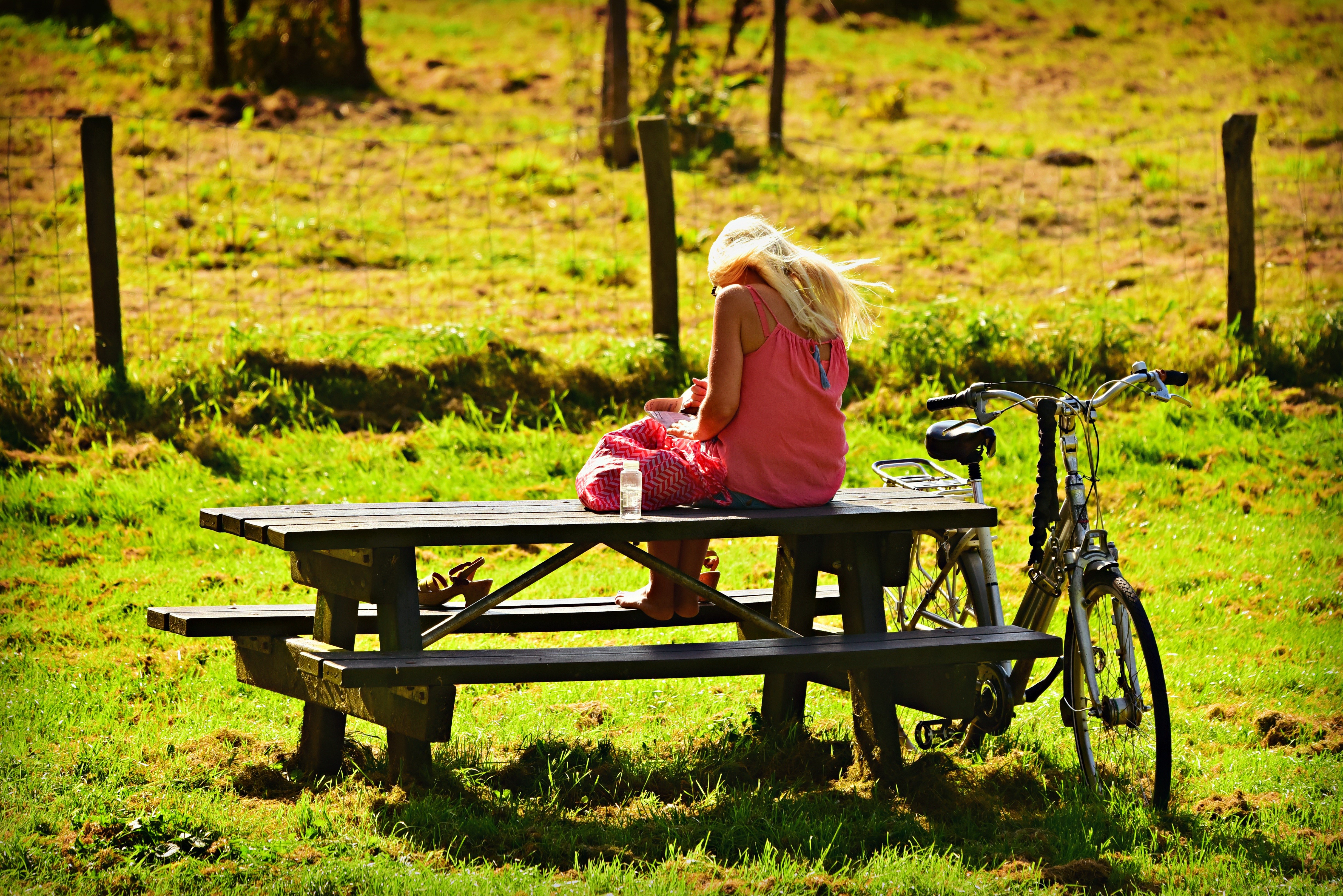 Blonde girl sitting on a picnic table with a bicycle HD Wallpaper