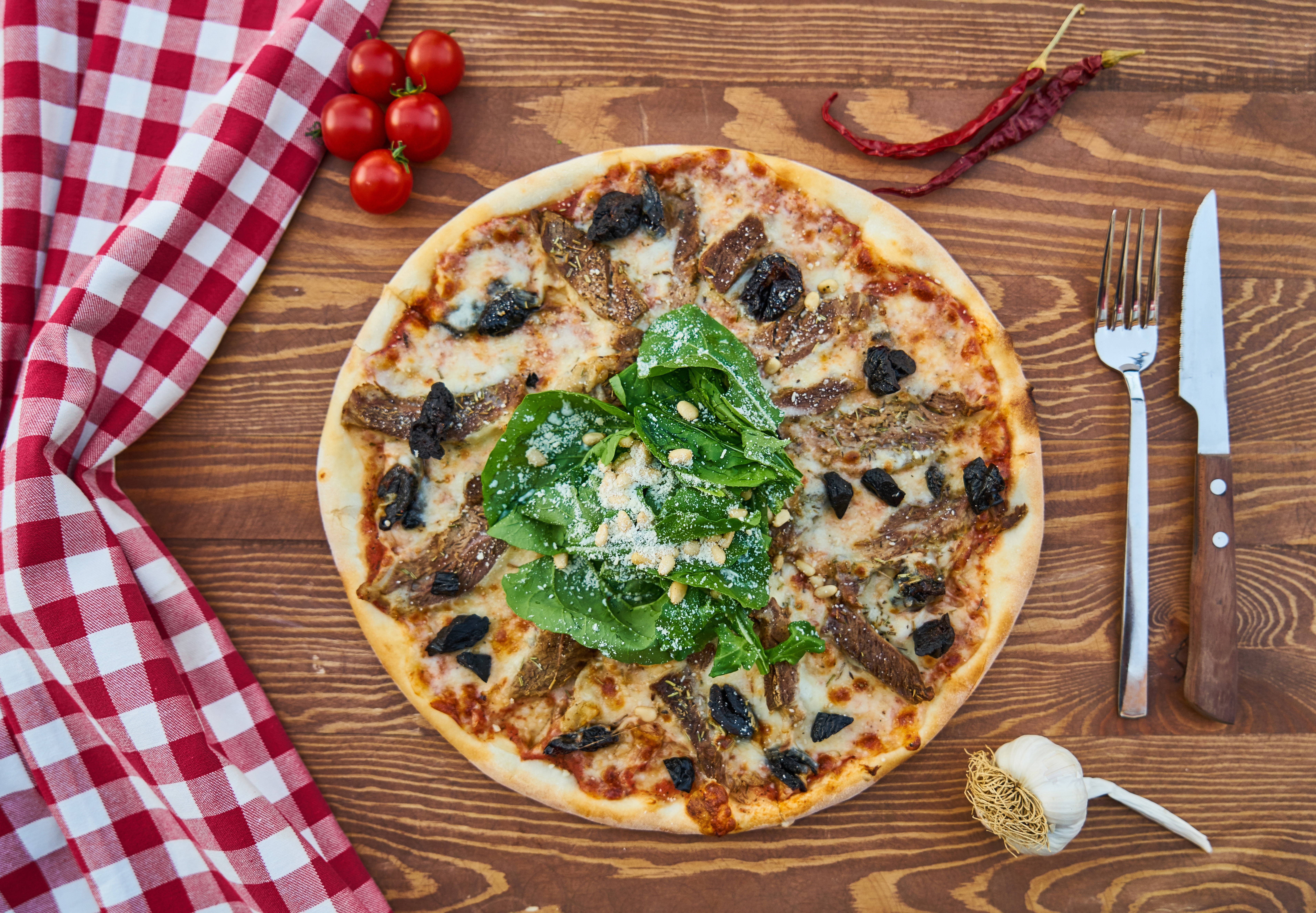 Pizza with tomatoes, chili peppers, garlic, knife, and fork HD Wallpaper