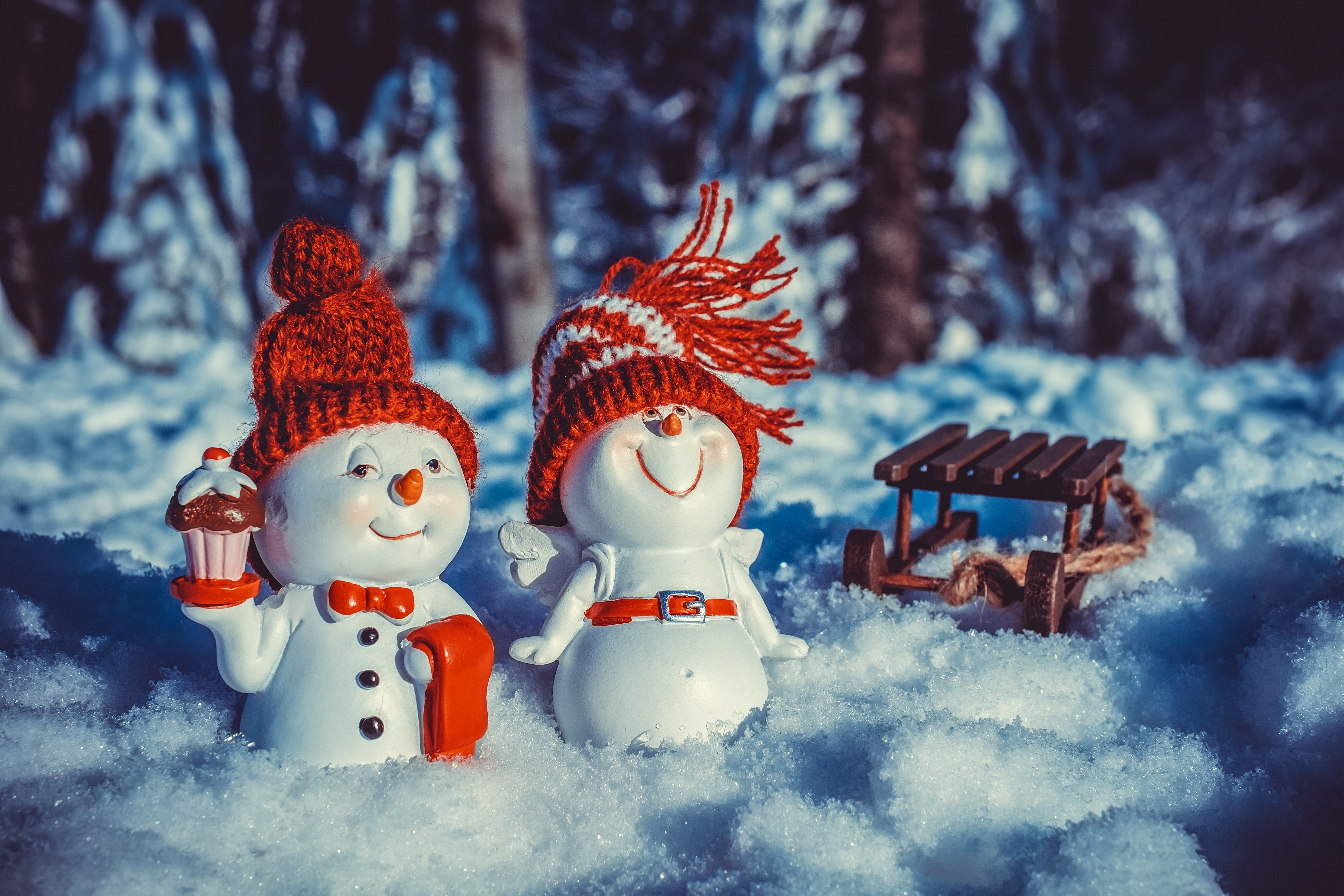 Two snowmen with winter hats and a sled in the snow HD Wallpaper