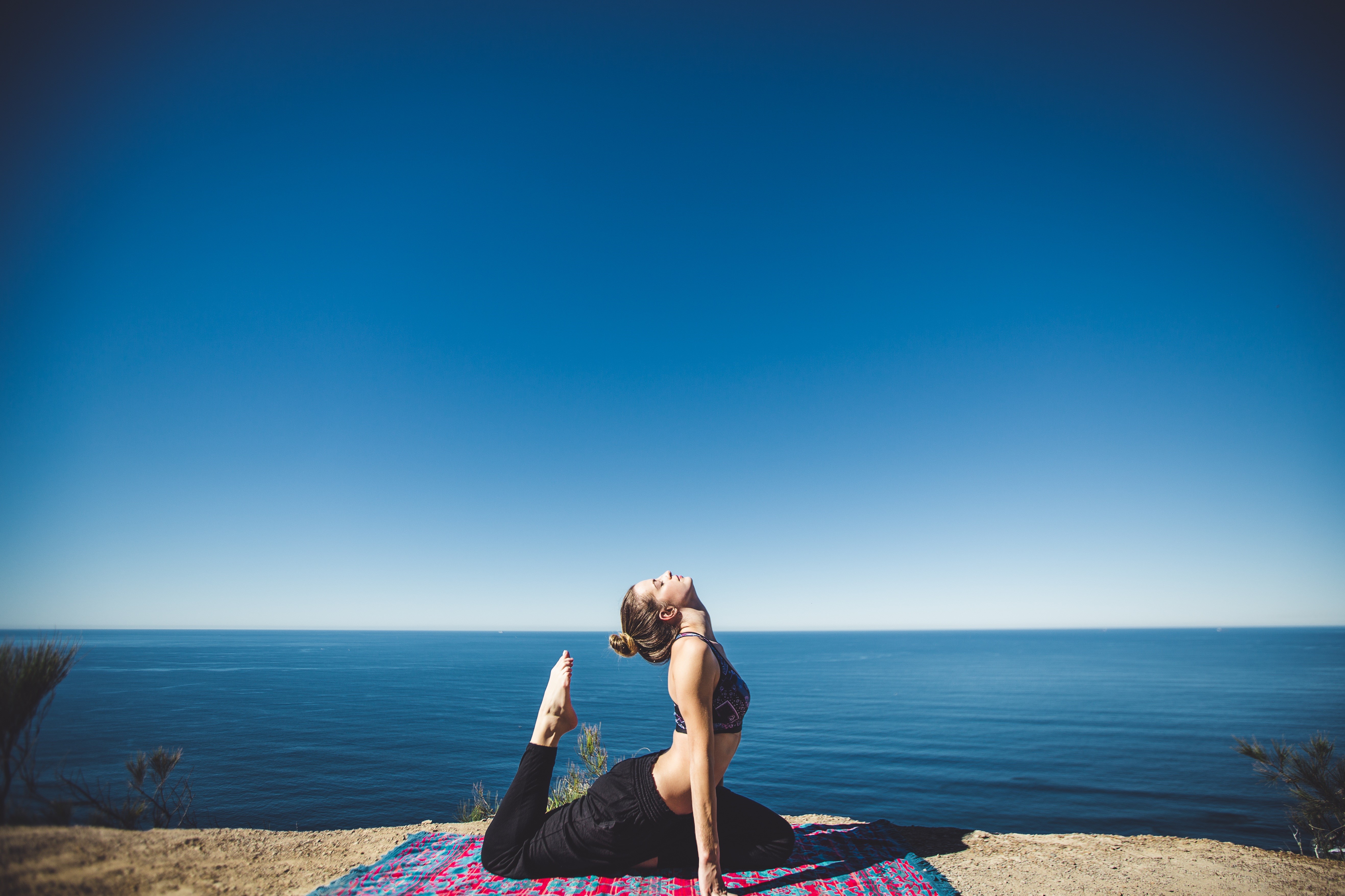 Woman doing yoga on a cliff overlooking the sea HD Wallpaper