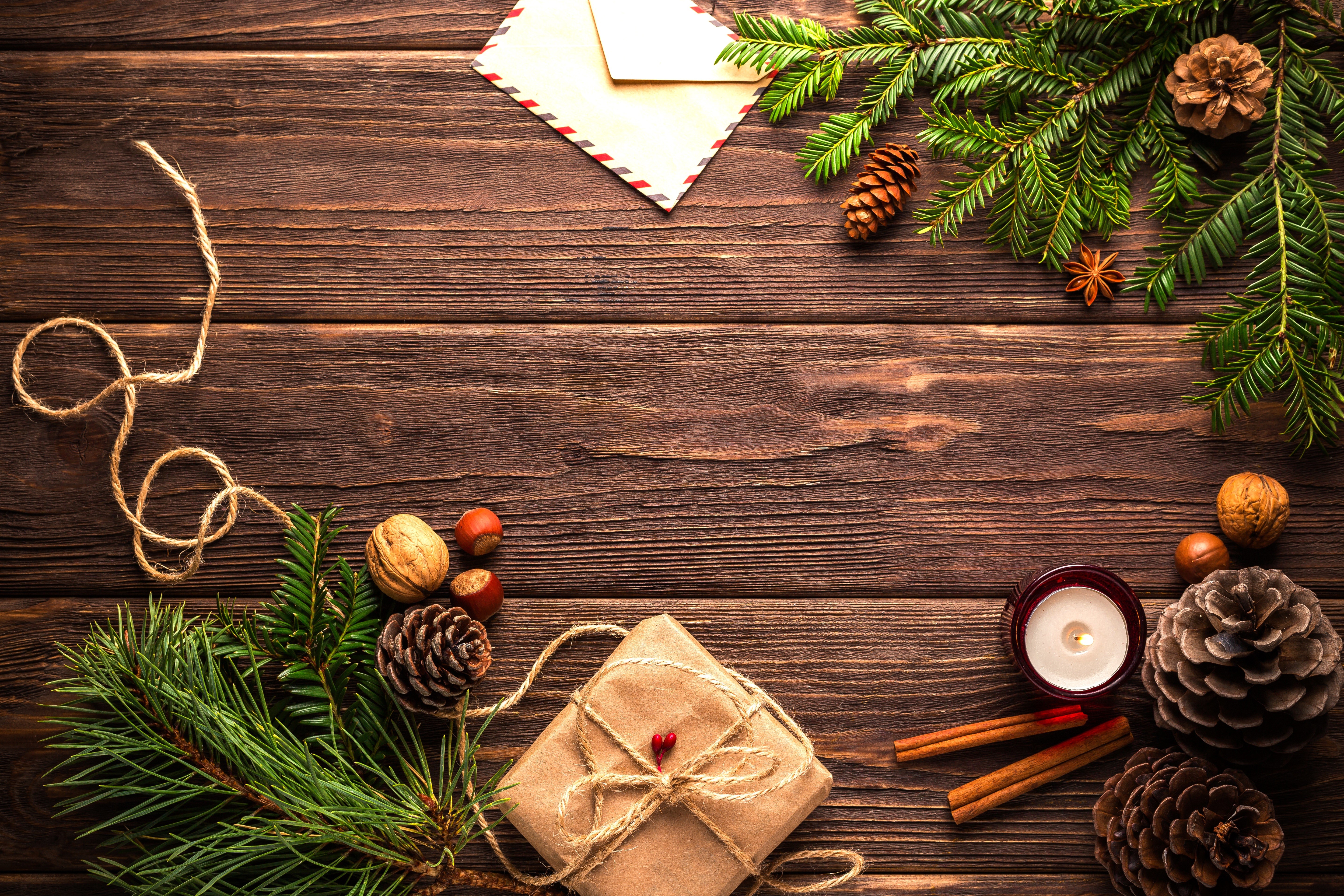 Christmas gift, pine cones, nuts, candle, and envelope on wood HD Wallpaper