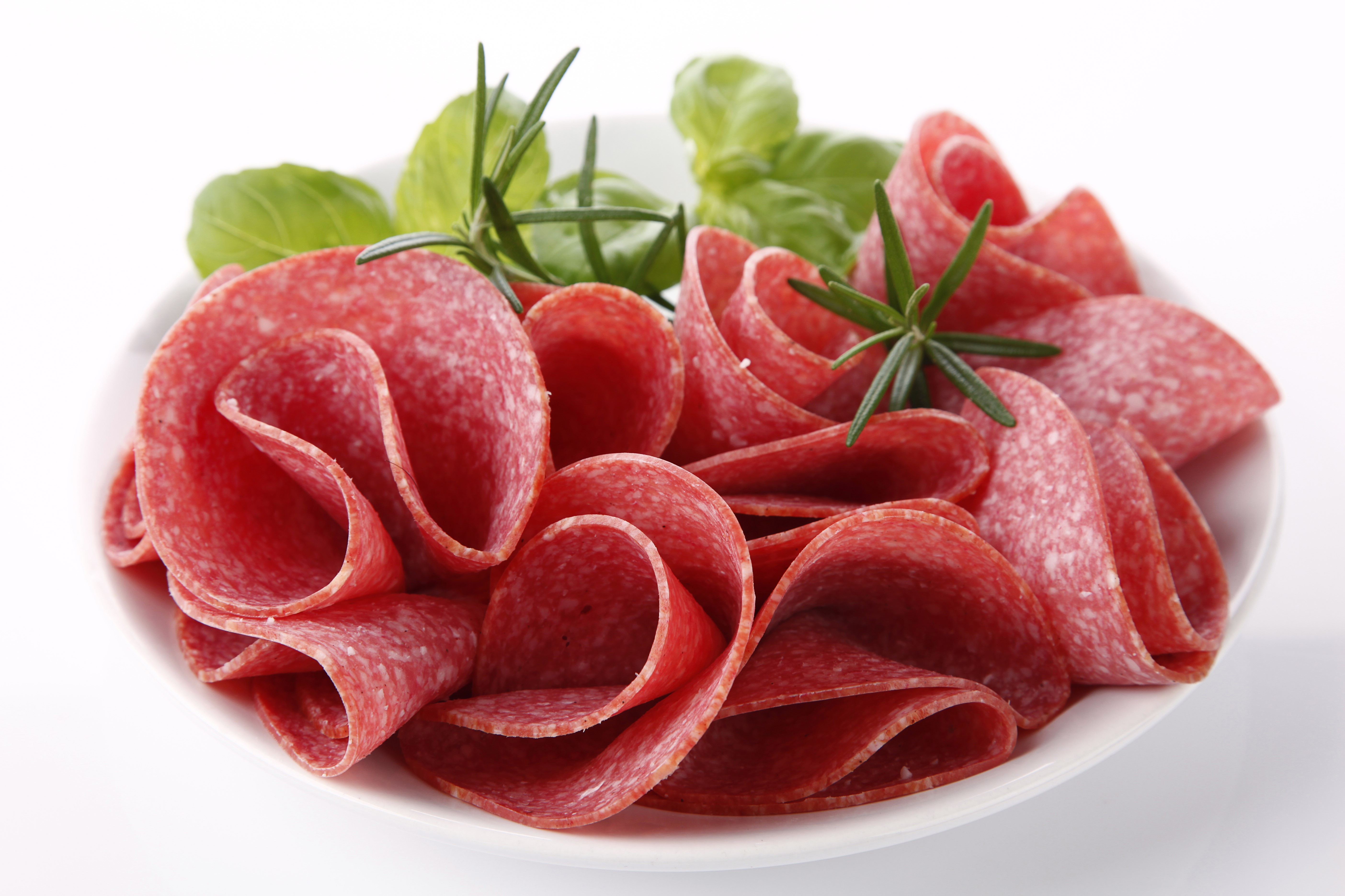 Sliced salami with herbs on a white plate HD Wallpaper