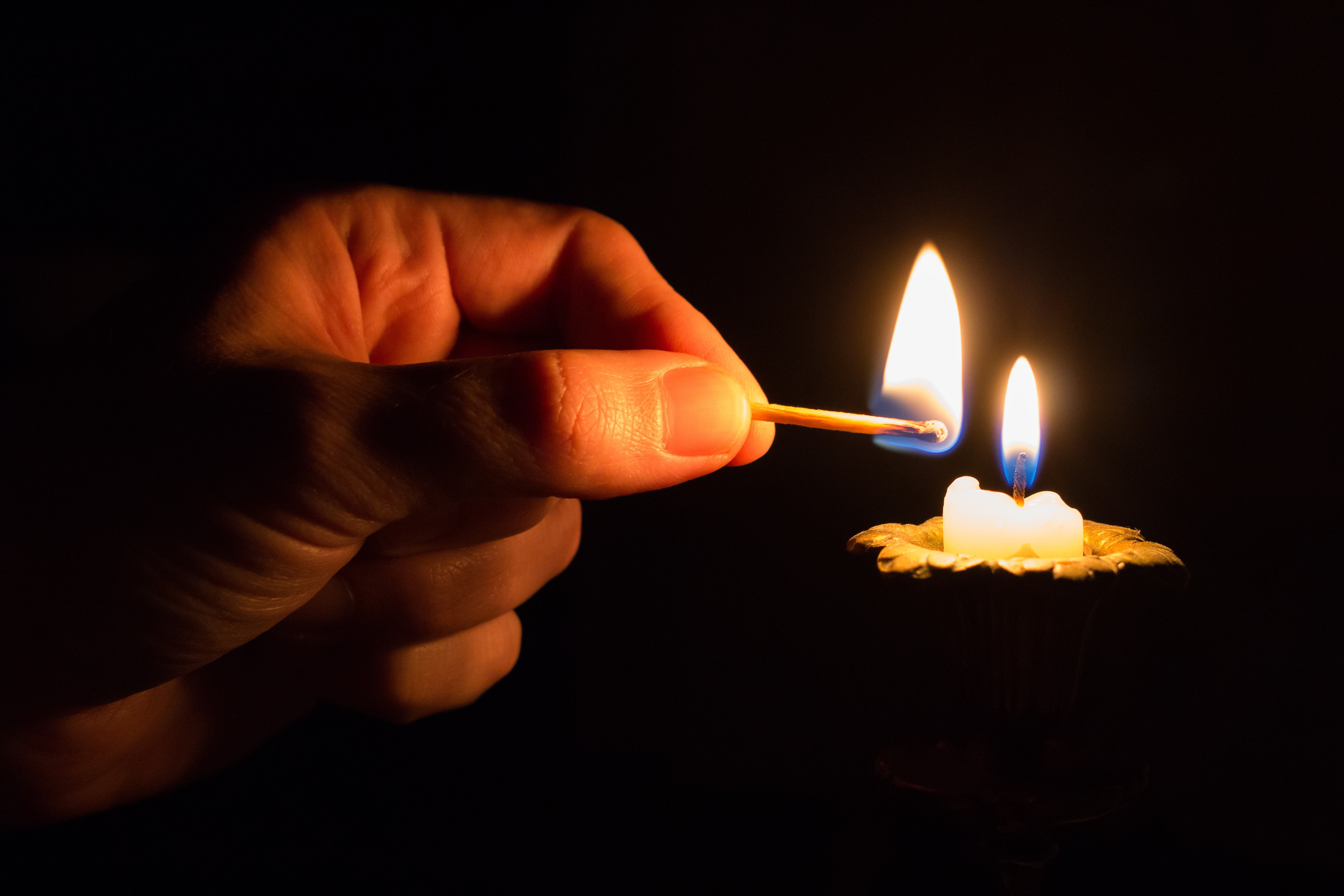 Hand lighting a candle with a match HD Wallpaper