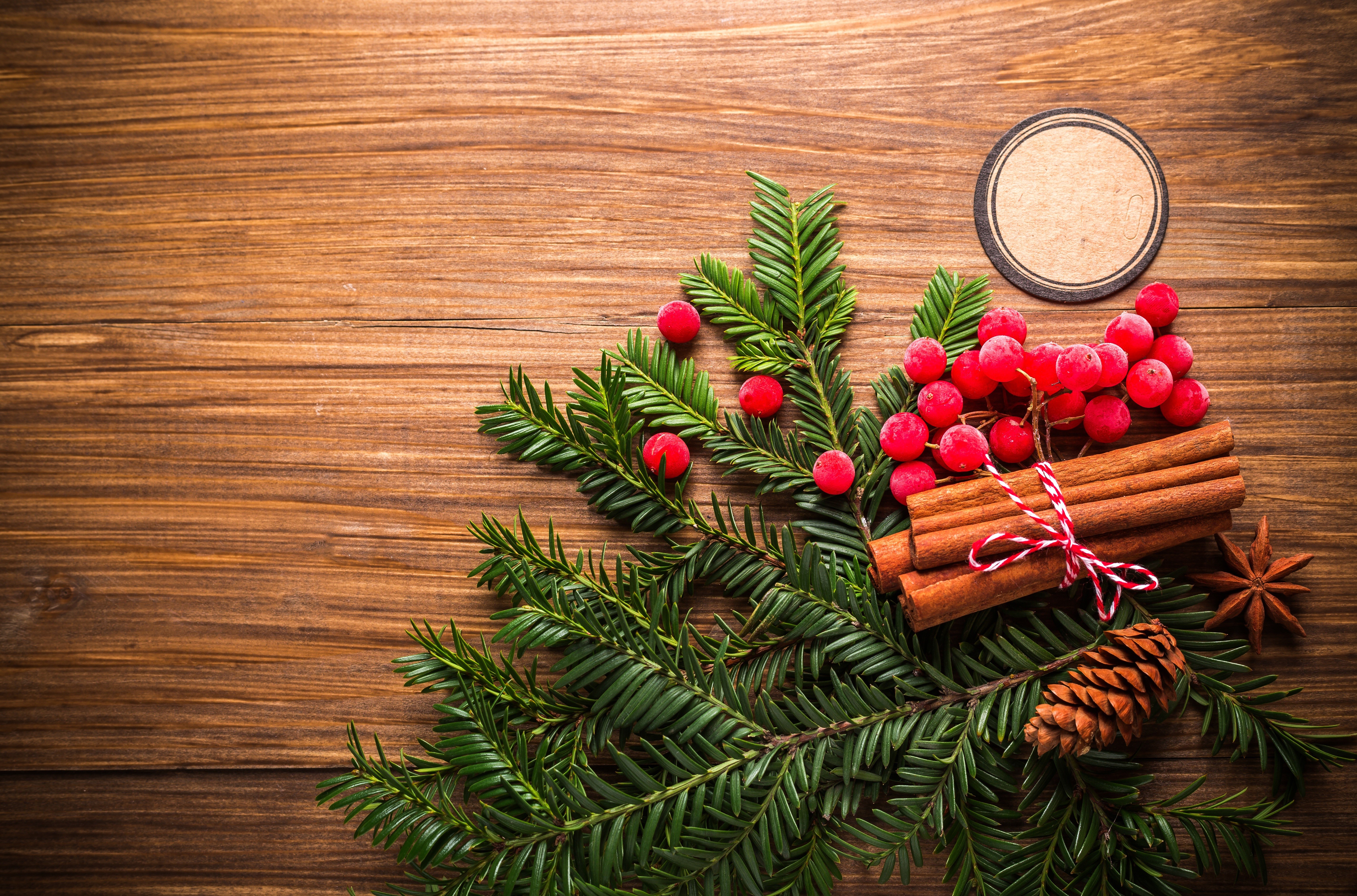 Christmas decoration with pine cone, berries, and cinnamon sticks on wood HD Wallpaper