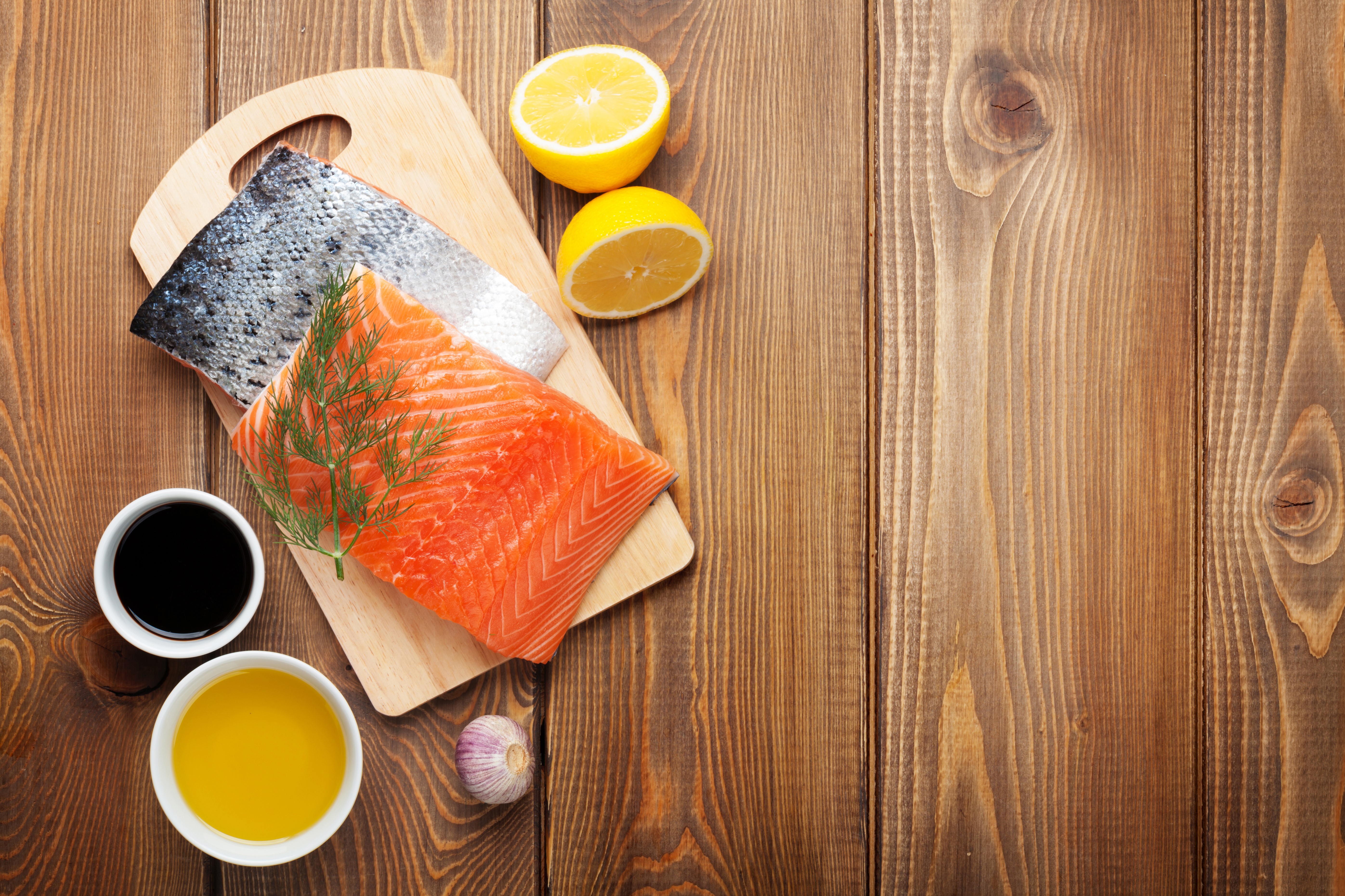 Salmon fillet with lemons, dill, garlic, soy sauce, and olive oil on a cutting board HD Wallpaper