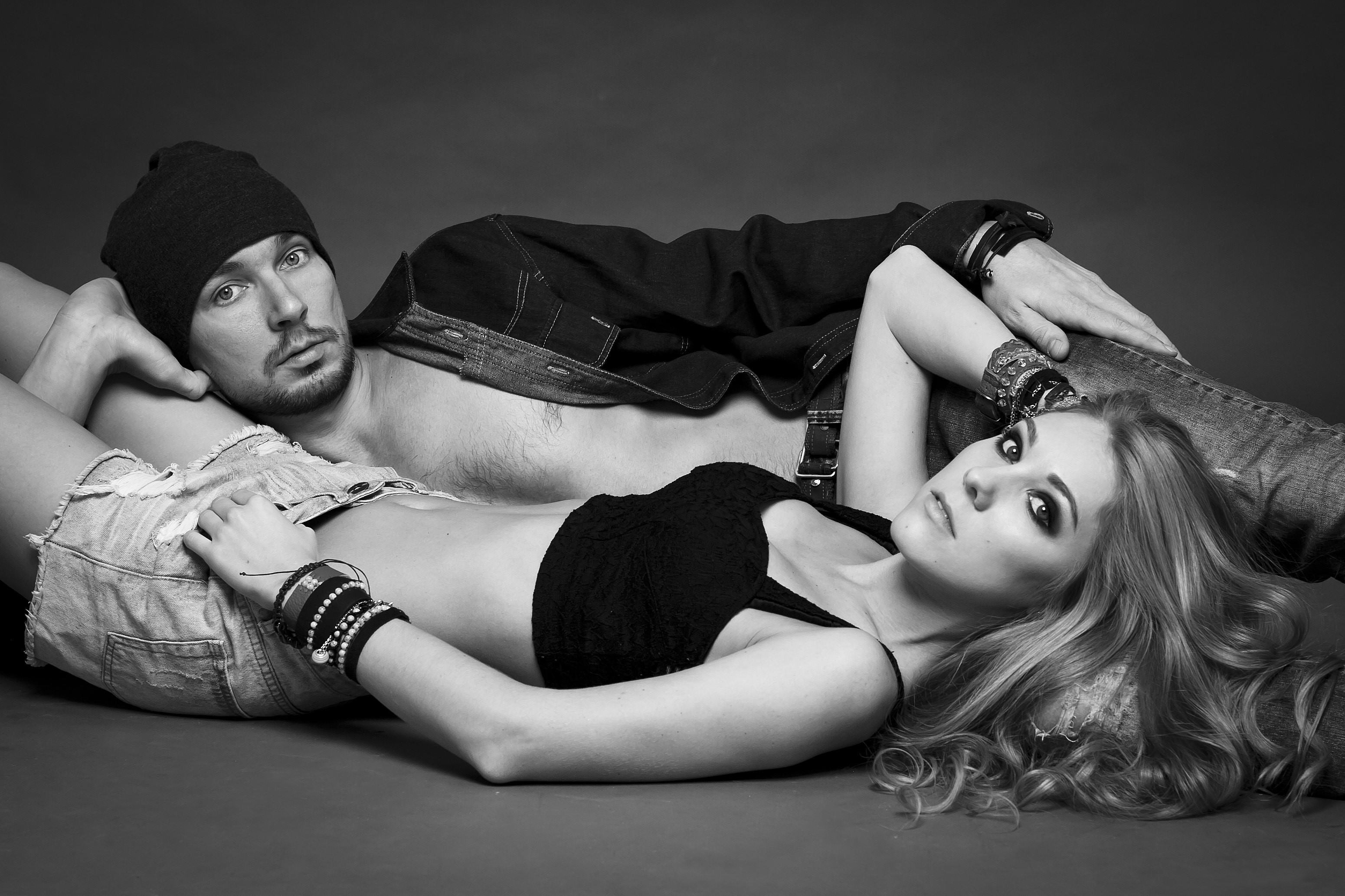 Man in winter hat and woman in shorts lying down HD Wallpaper