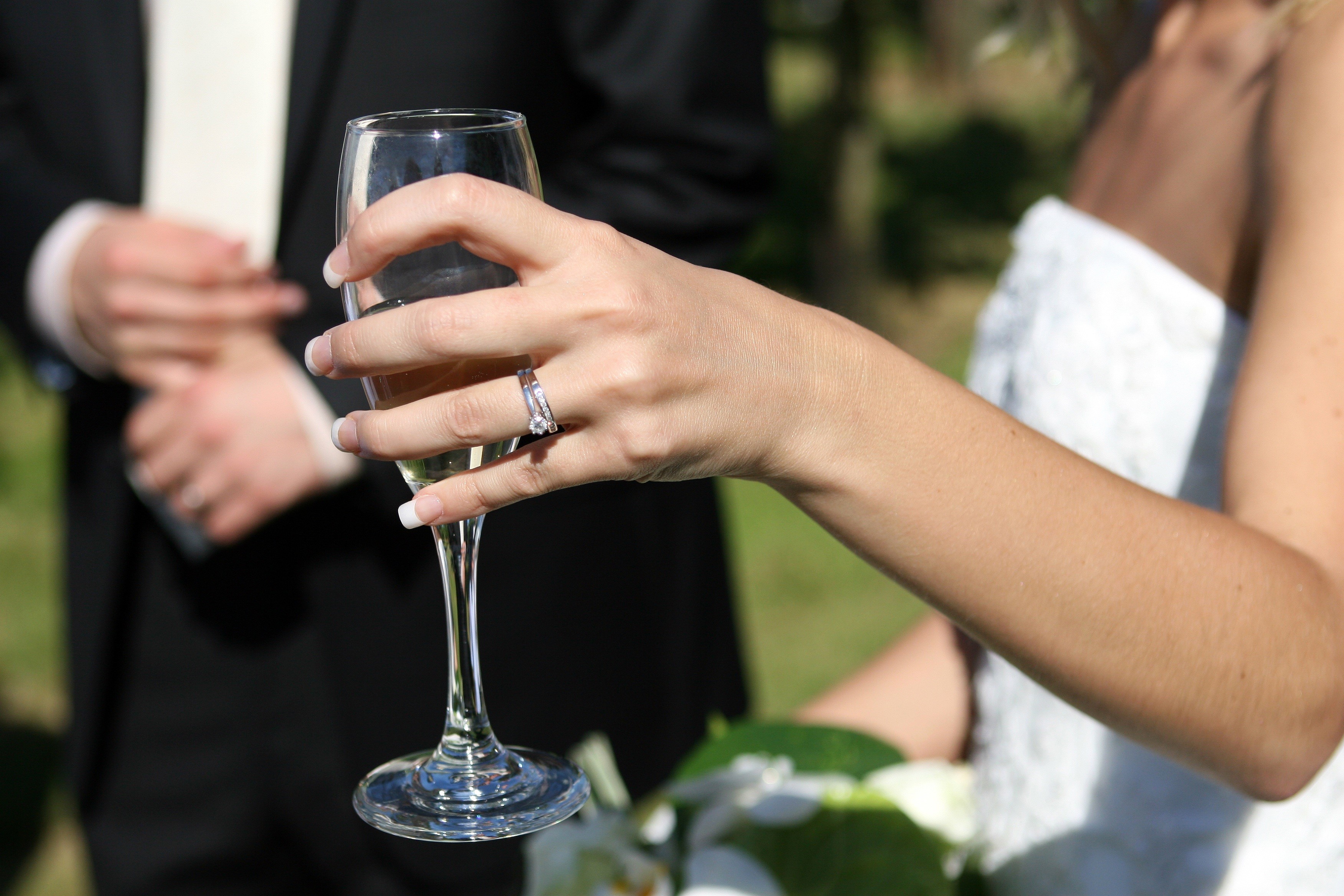 Bride holding champagne glass with groom in background HD Wallpaper