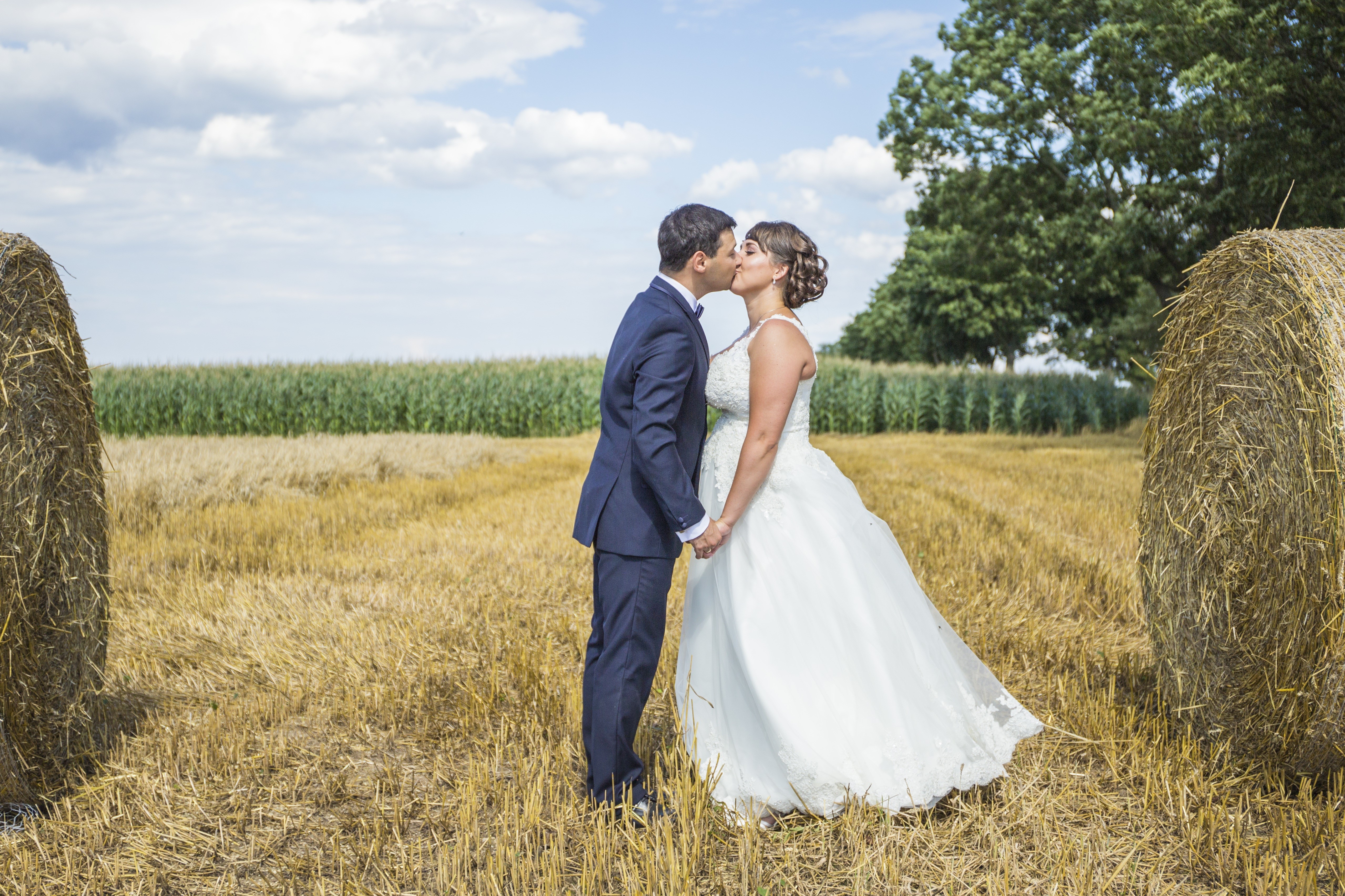 Bride and Groom kissing in a field with hay bales HD Wallpaper