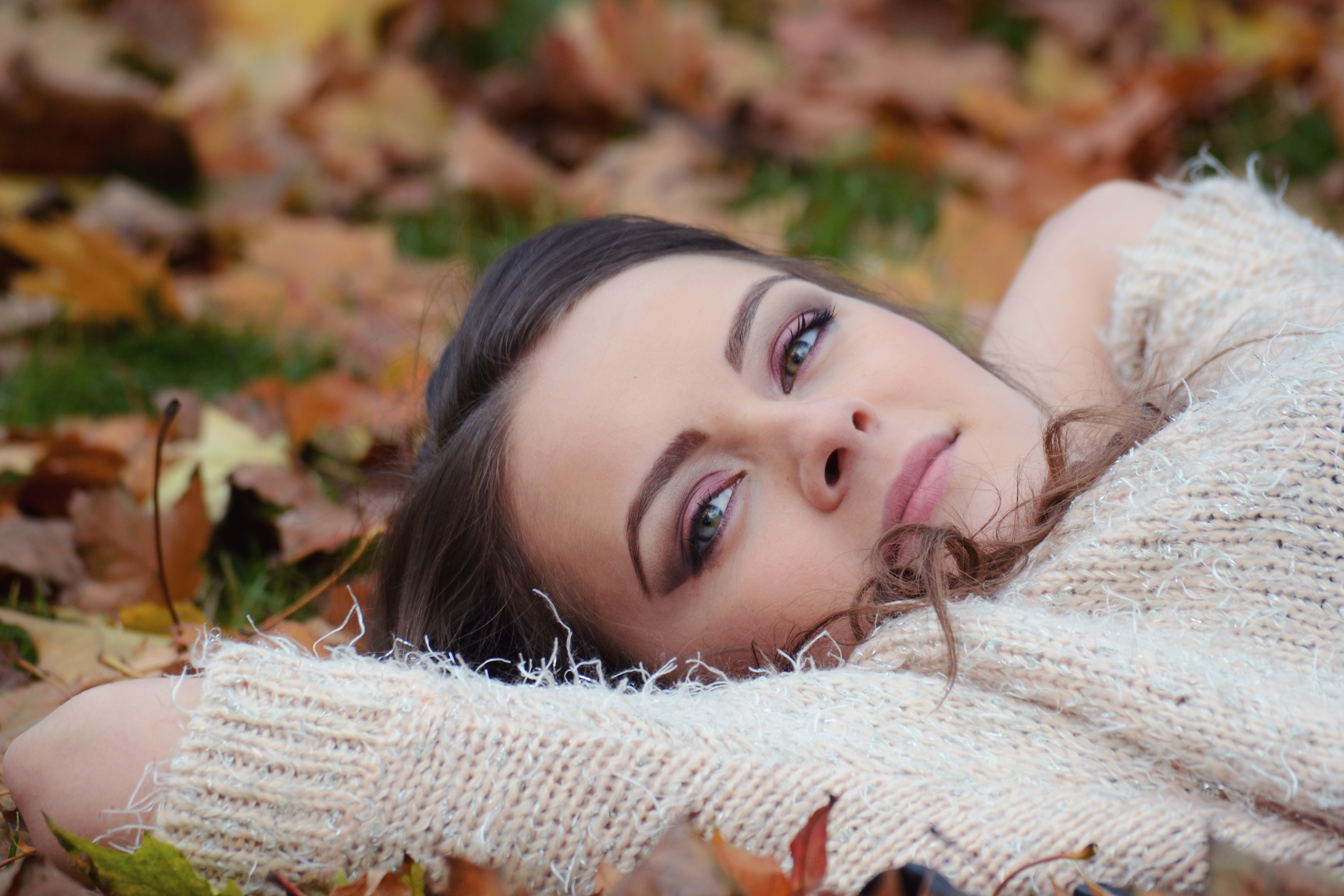 Woman in Sweater Lying in Autumn Foliage HD Wallpaper