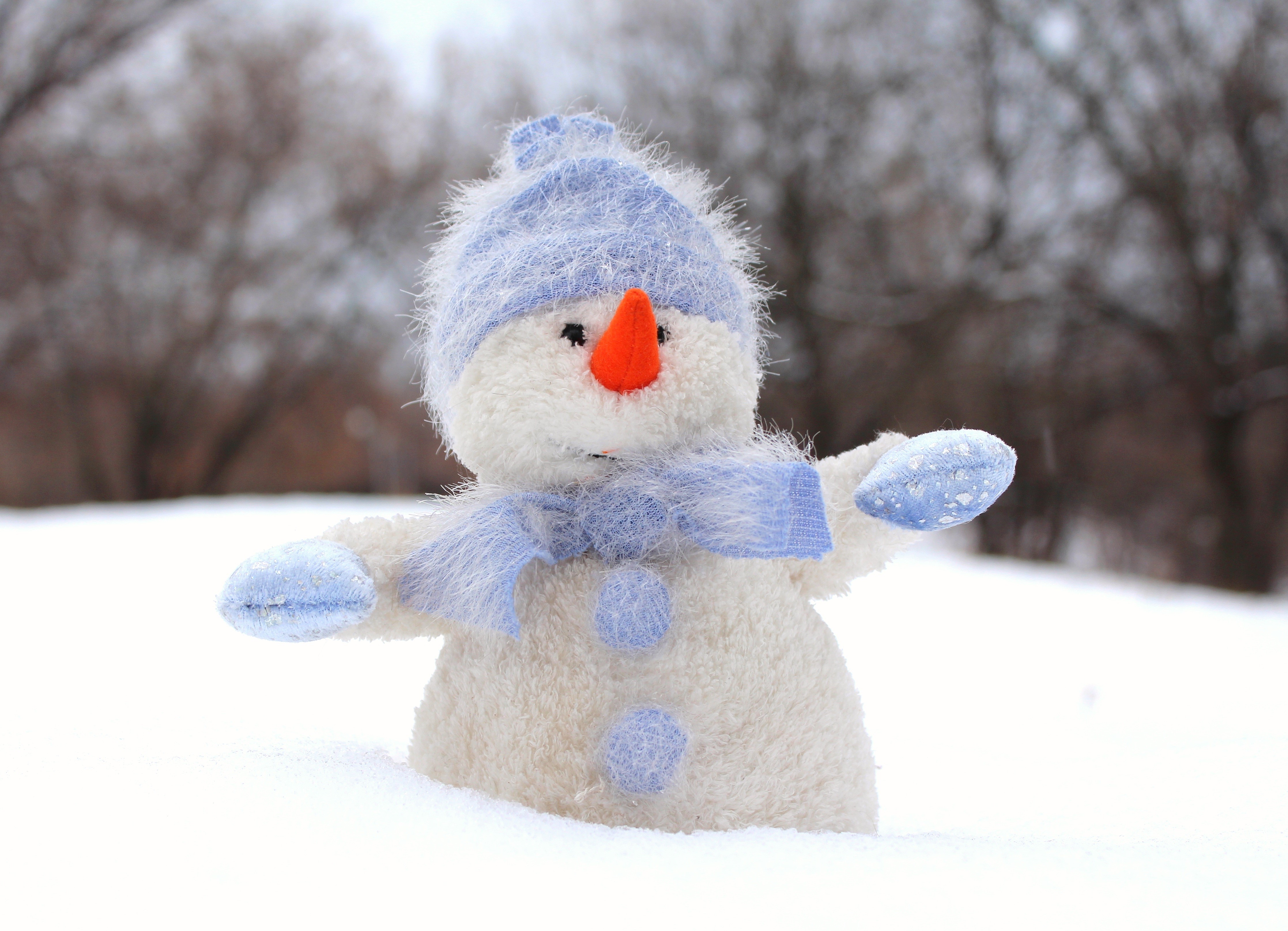 Plush snowman with blue hat and scarf in snow HD Wallpaper