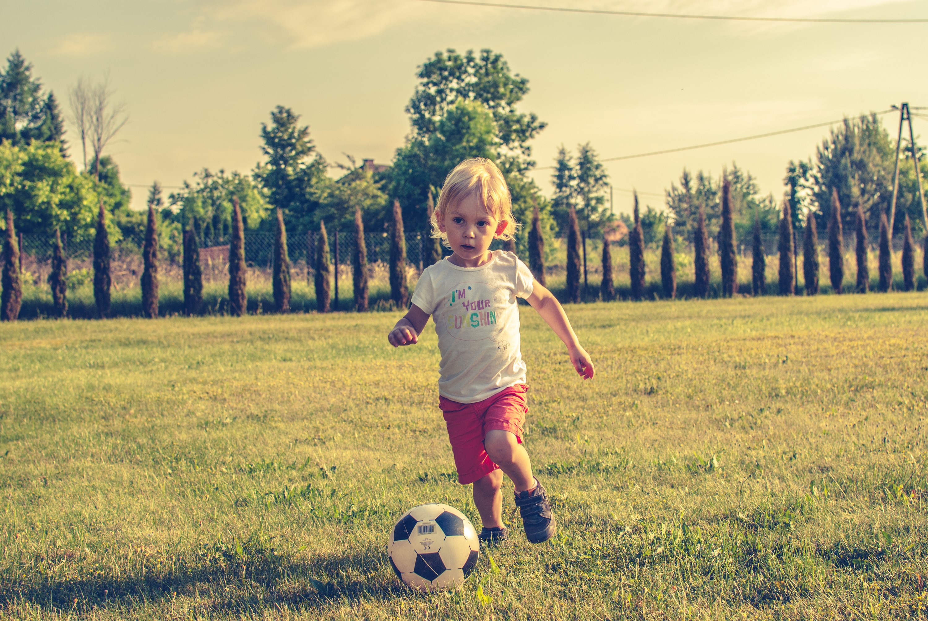 Young boy playing soccer on a grassy field HD Wallpaper