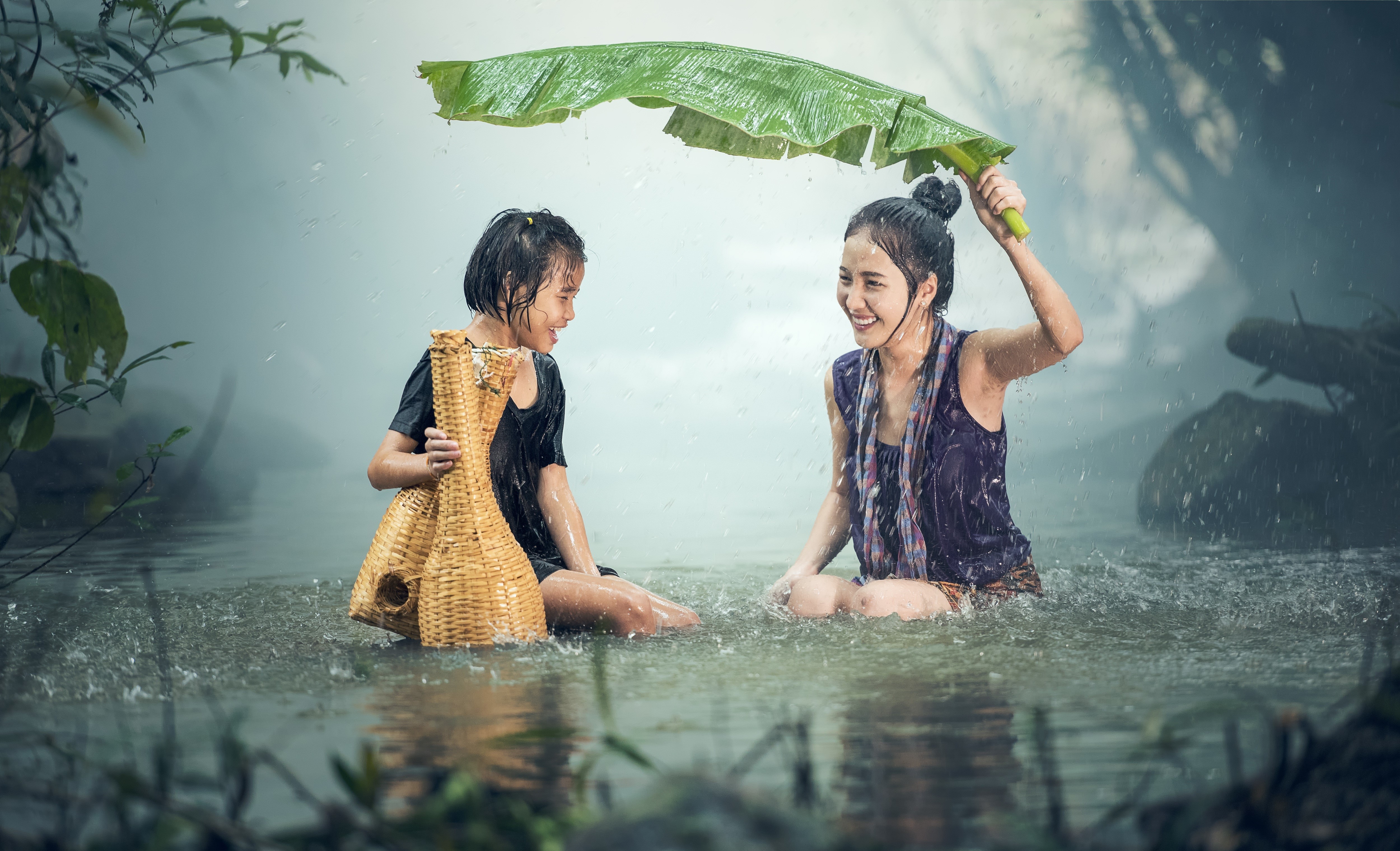 Two Little Girls Laughing and Sitting in Rain with Banana Leaf HD Wallpaper