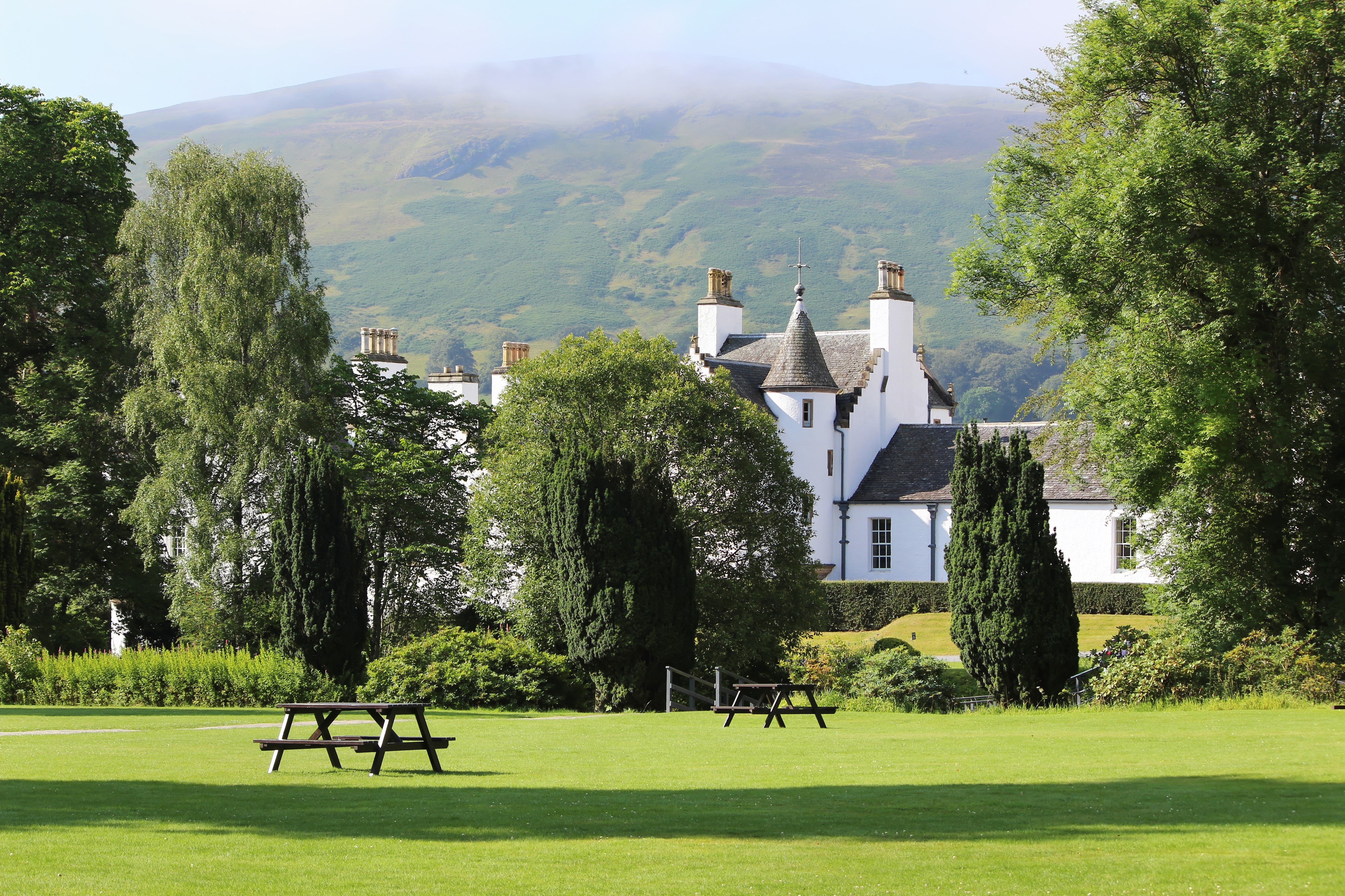 White castle with picnic tables on a lawn in Scotland HD Wallpaper