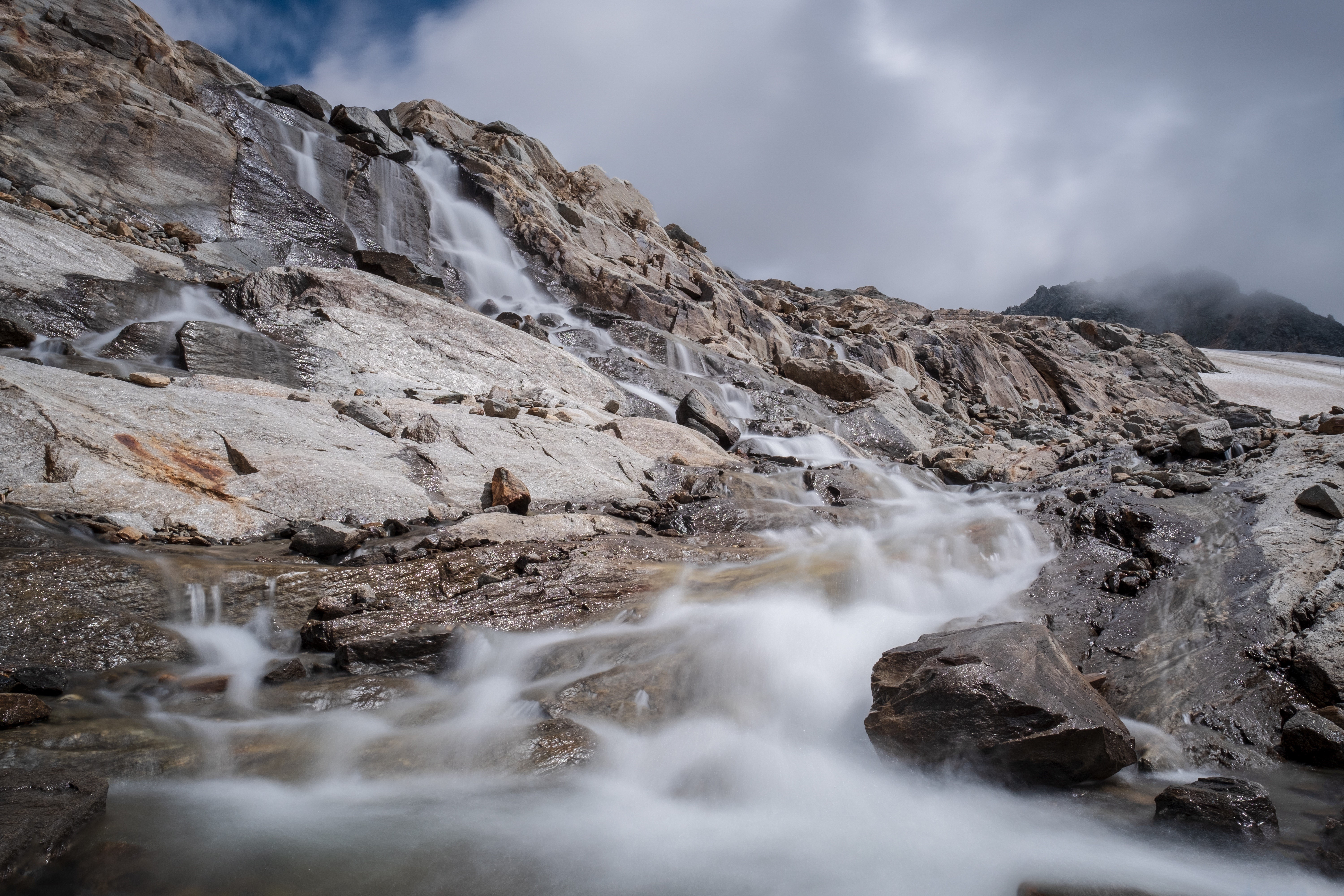 Waterfall cascading over rocky mountain slope HD Wallpaper