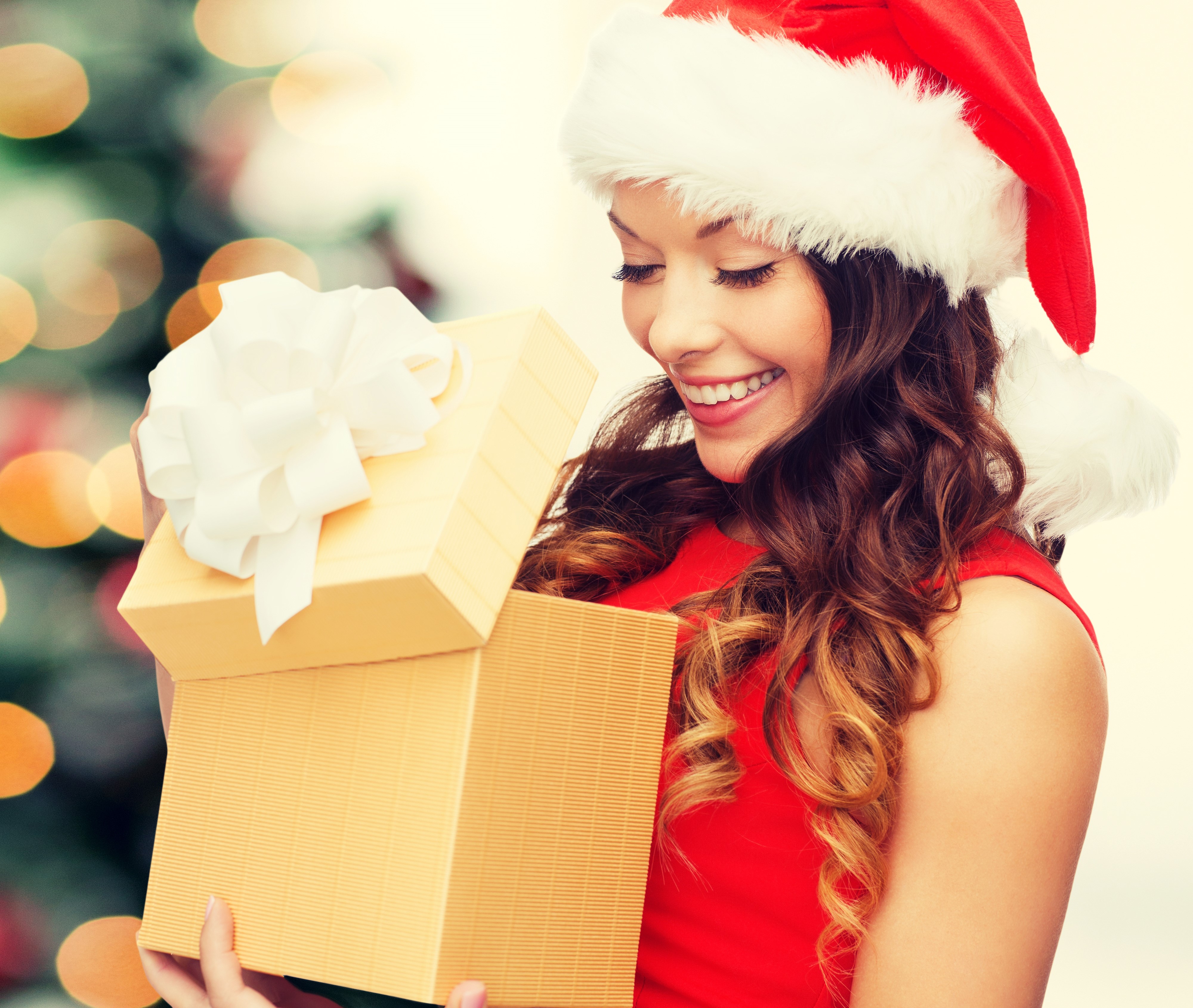 Woman in Santa hat opening Christmas gift HD Wallpaper