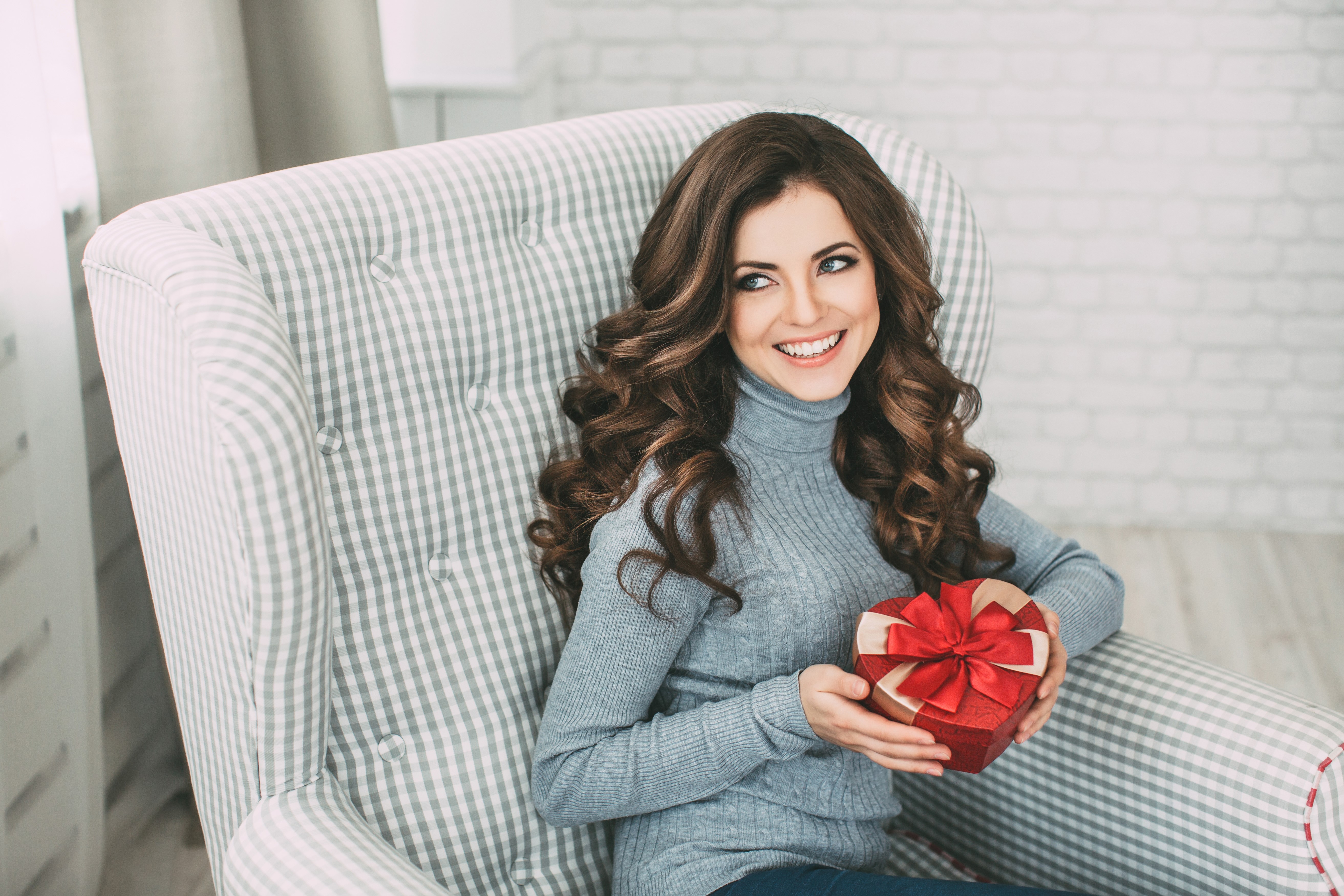 Woman in armchair holding a heart-shaped gift HD Wallpaper