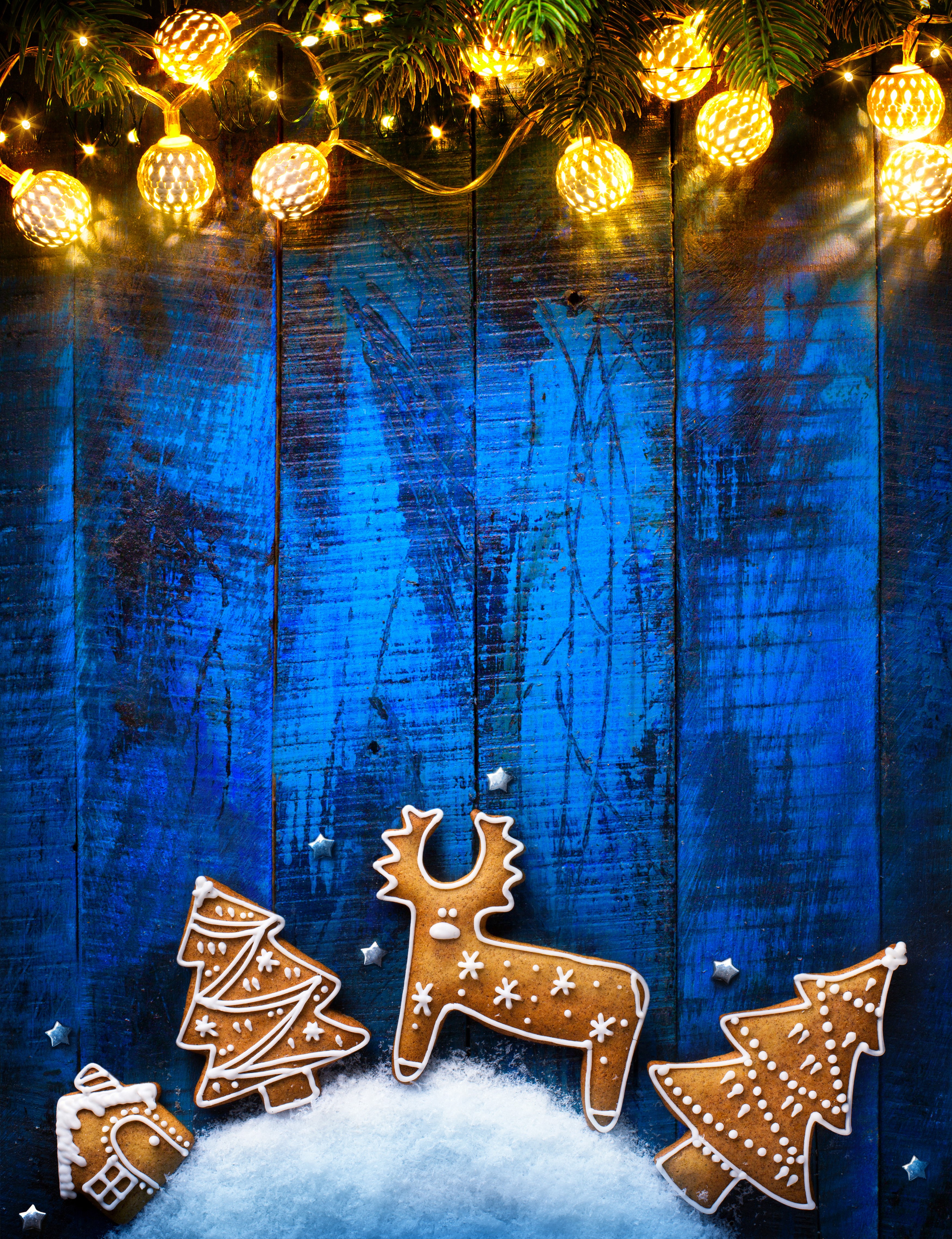 Christmas gingerbread cookies with fairy lights on blue wood HD Phone Wallpaper