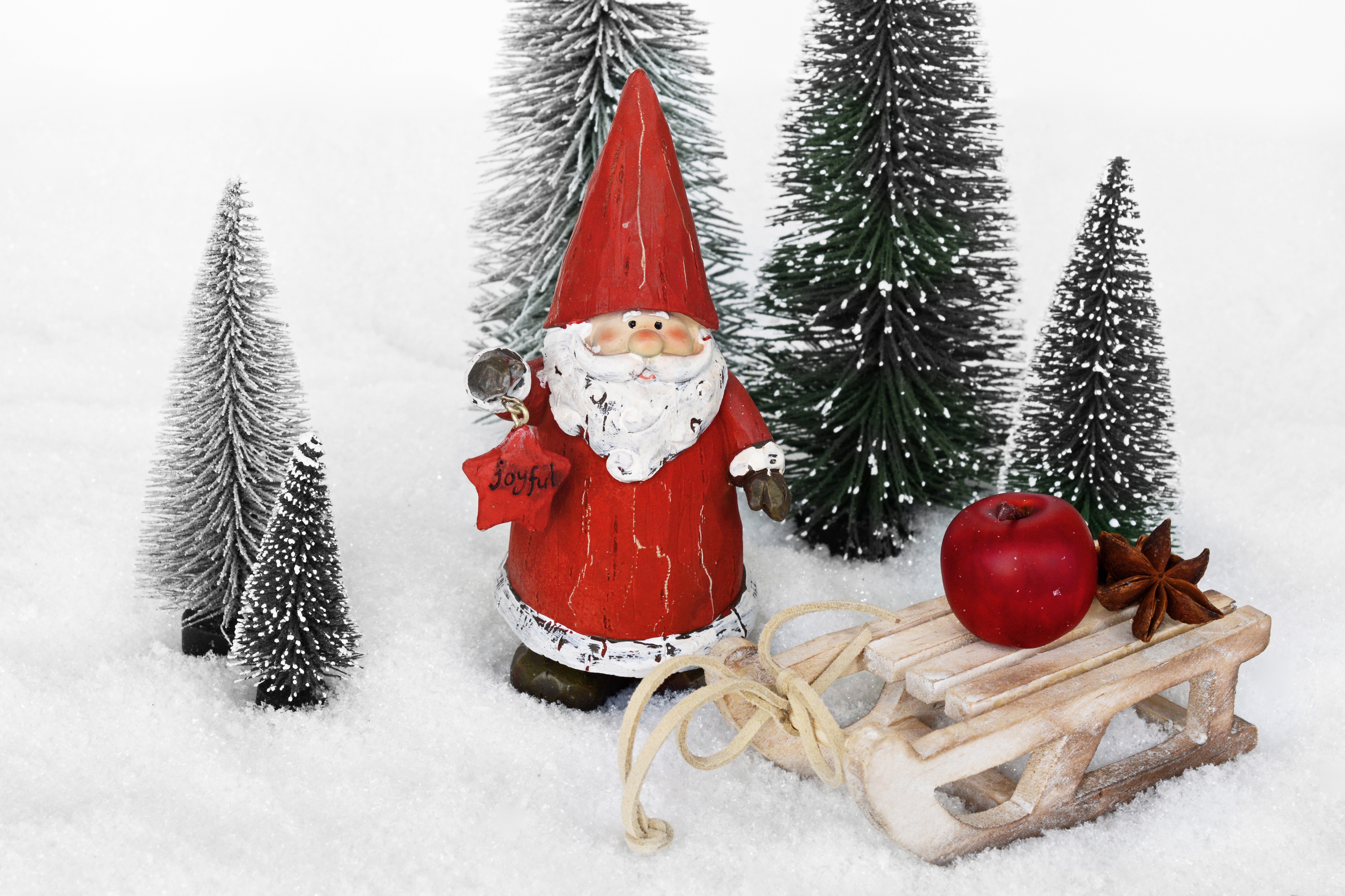 Santa Claus figurine with sled, apple, and trees in snow HD Wallpaper