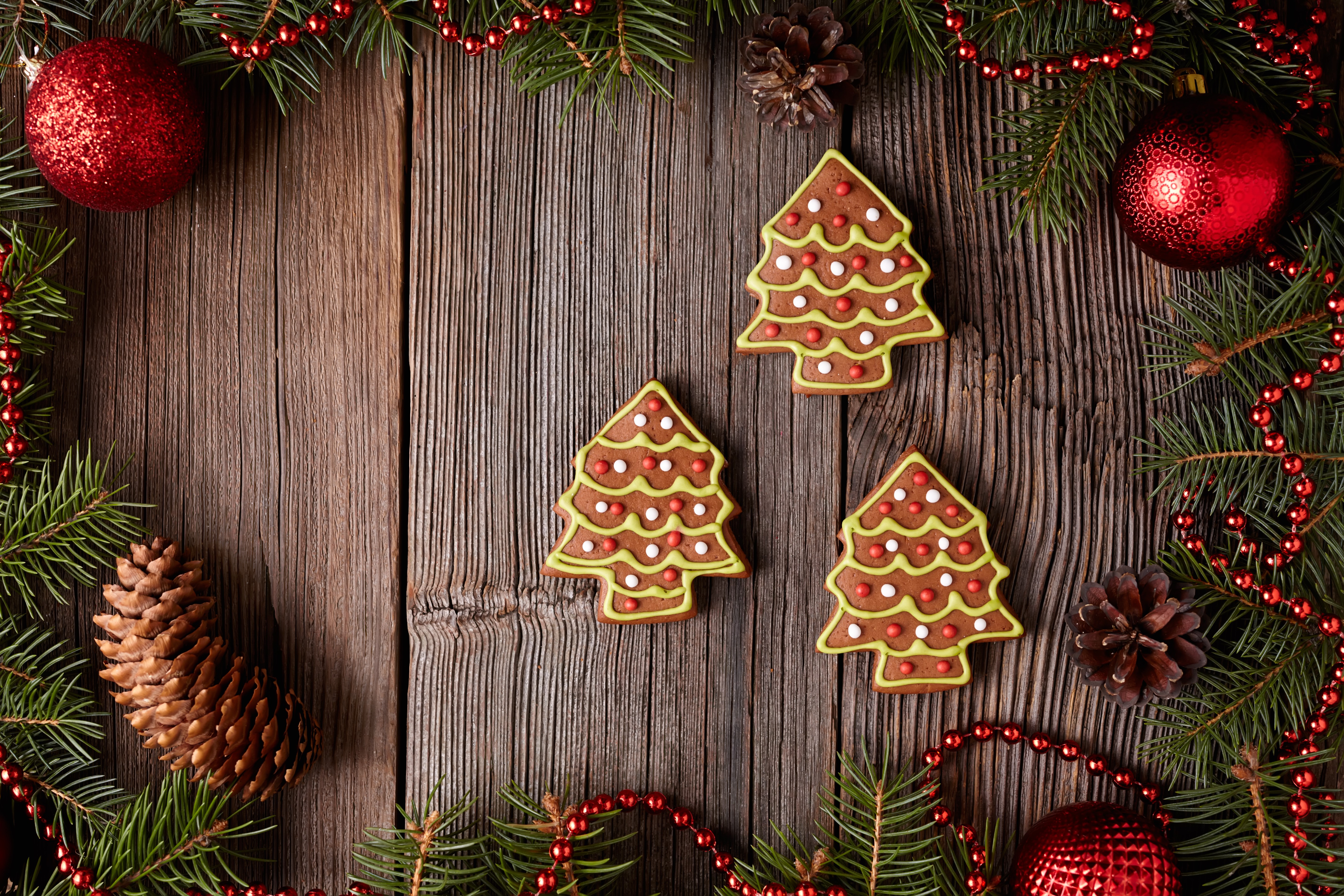 Christmas tree cookies on wooden planks with pine cones and ornaments HD Wallpaper