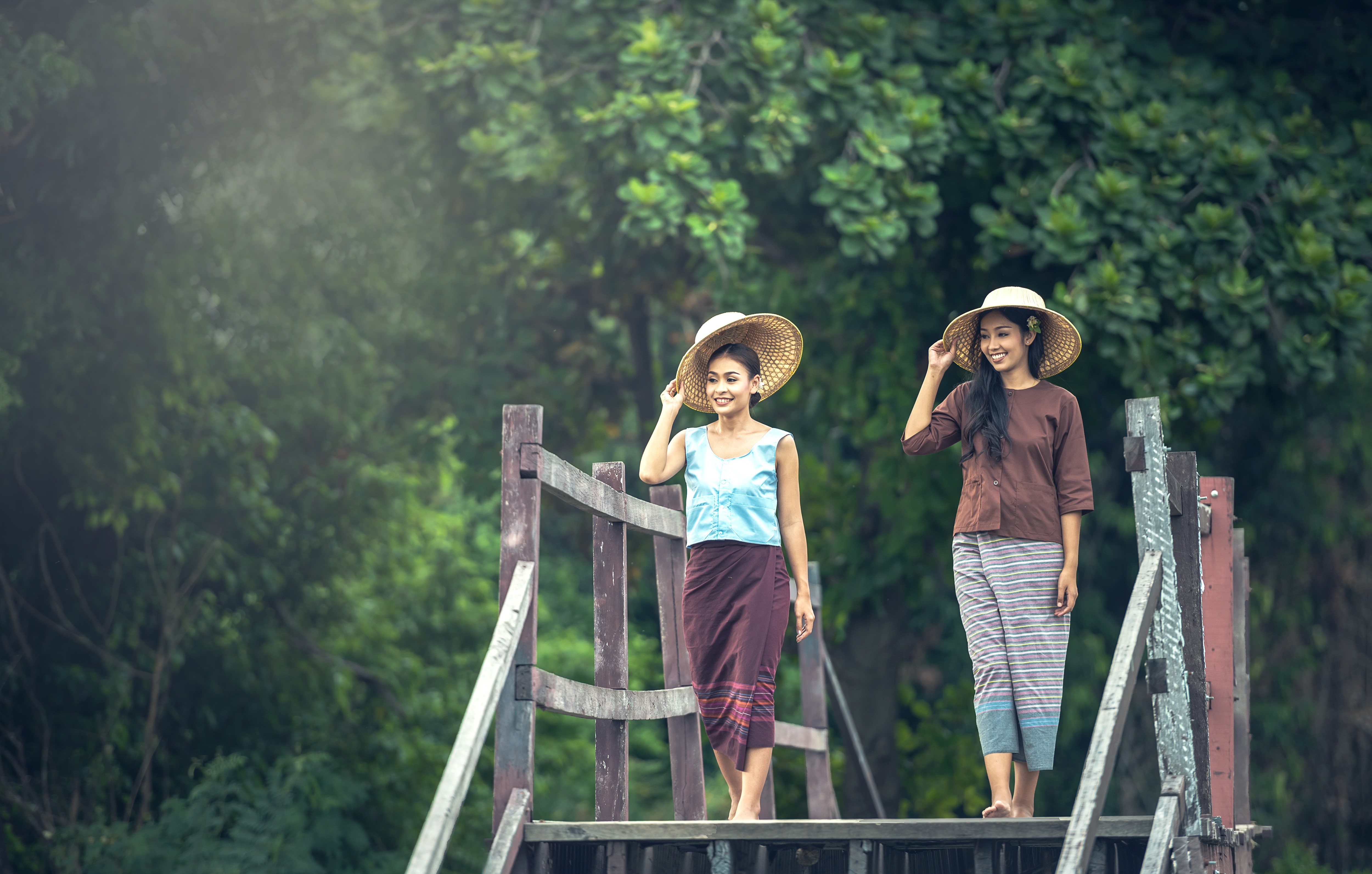 Two Asian women in traditional clothing and hats on a wooden bridge HD Wallpaper