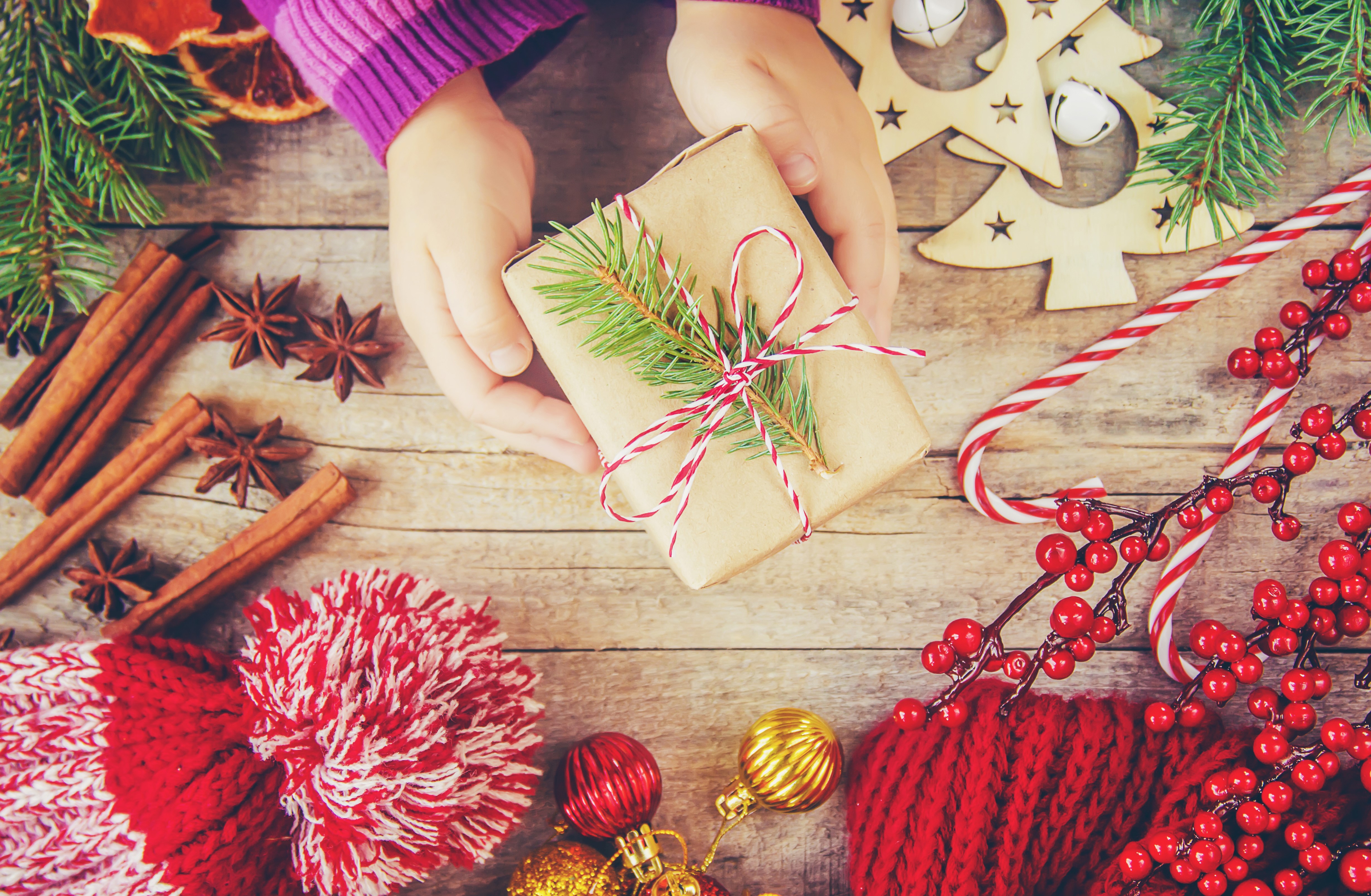 Hands holding a Christmas gift with festive decorations HD Wallpaper